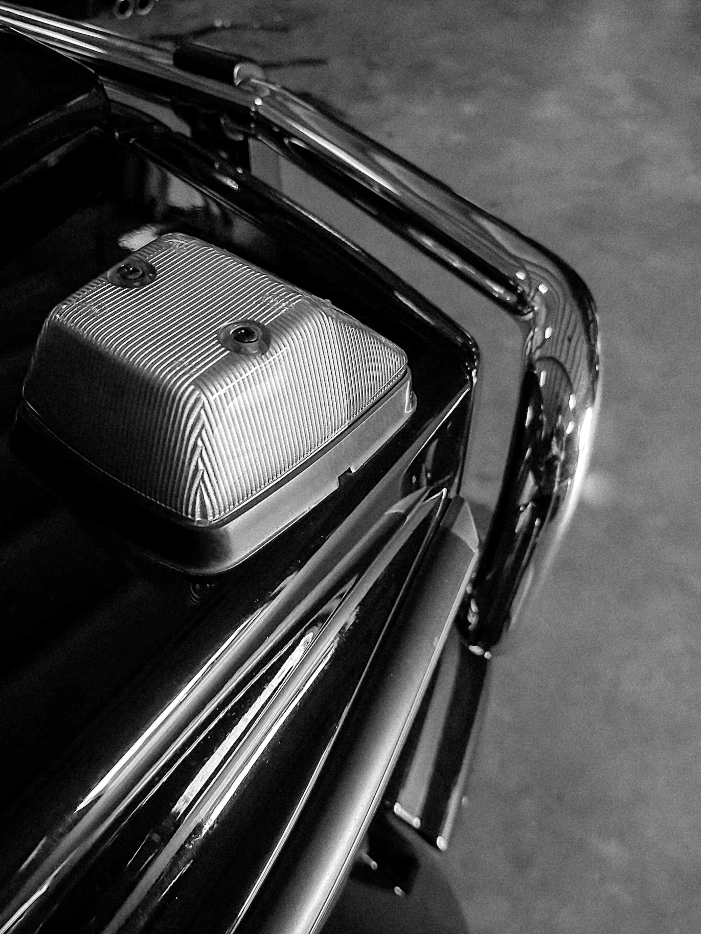 Close-up of a vintage police car's roof with a textured light and chrome detailing, in black and white.