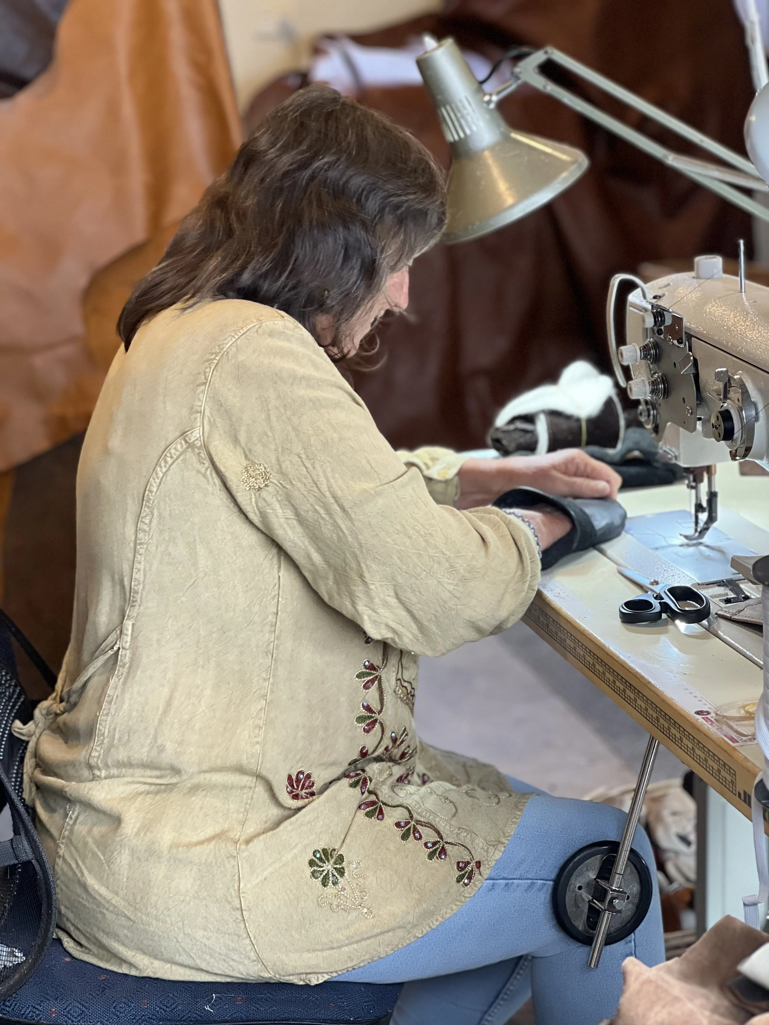 Person sewing using a sewing machine at a work table.