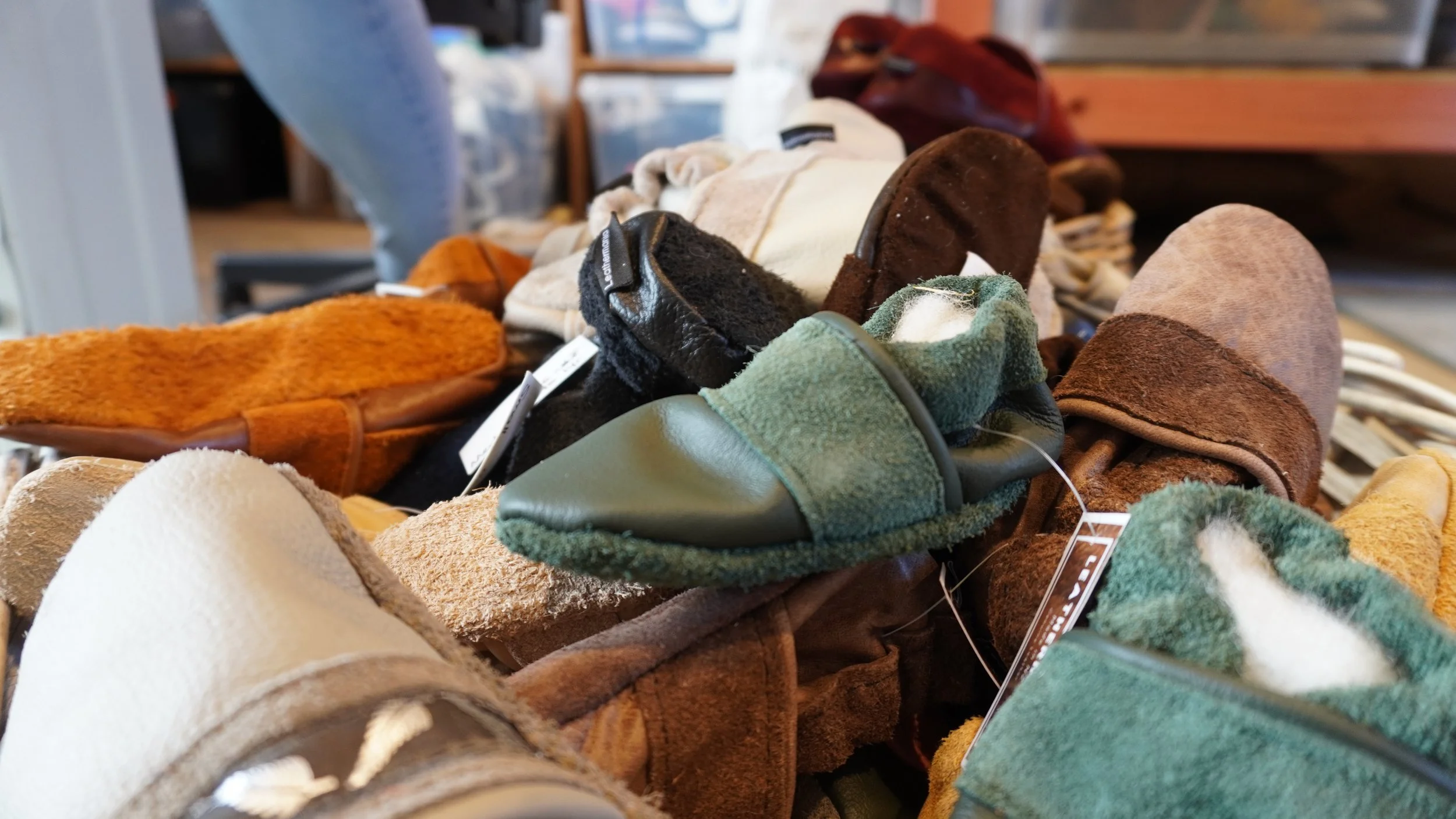 A collection of various slippers and slippers in different colors and materials displayed on a table in a store.