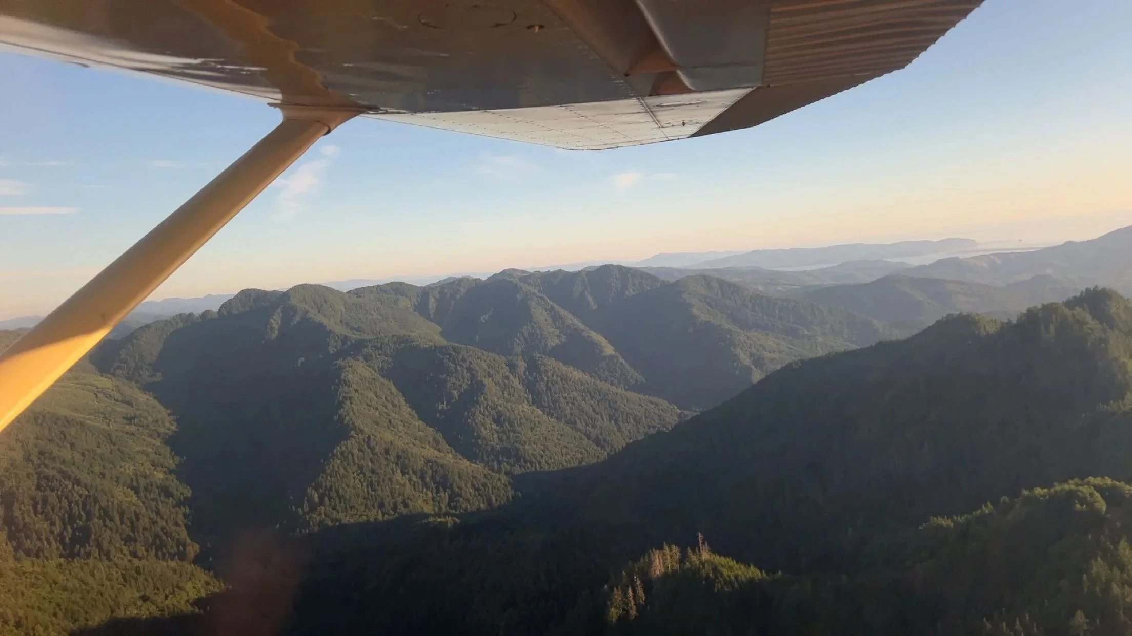 View from cockpit over forested Cascade Mountain ridges during pilot training flight