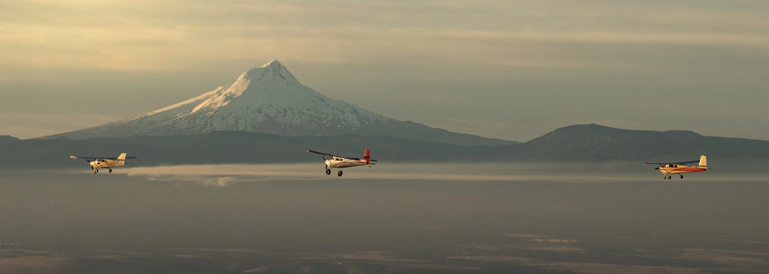 Three Cessna training aircraft flying in formation near Mount St. Helens during a training mission