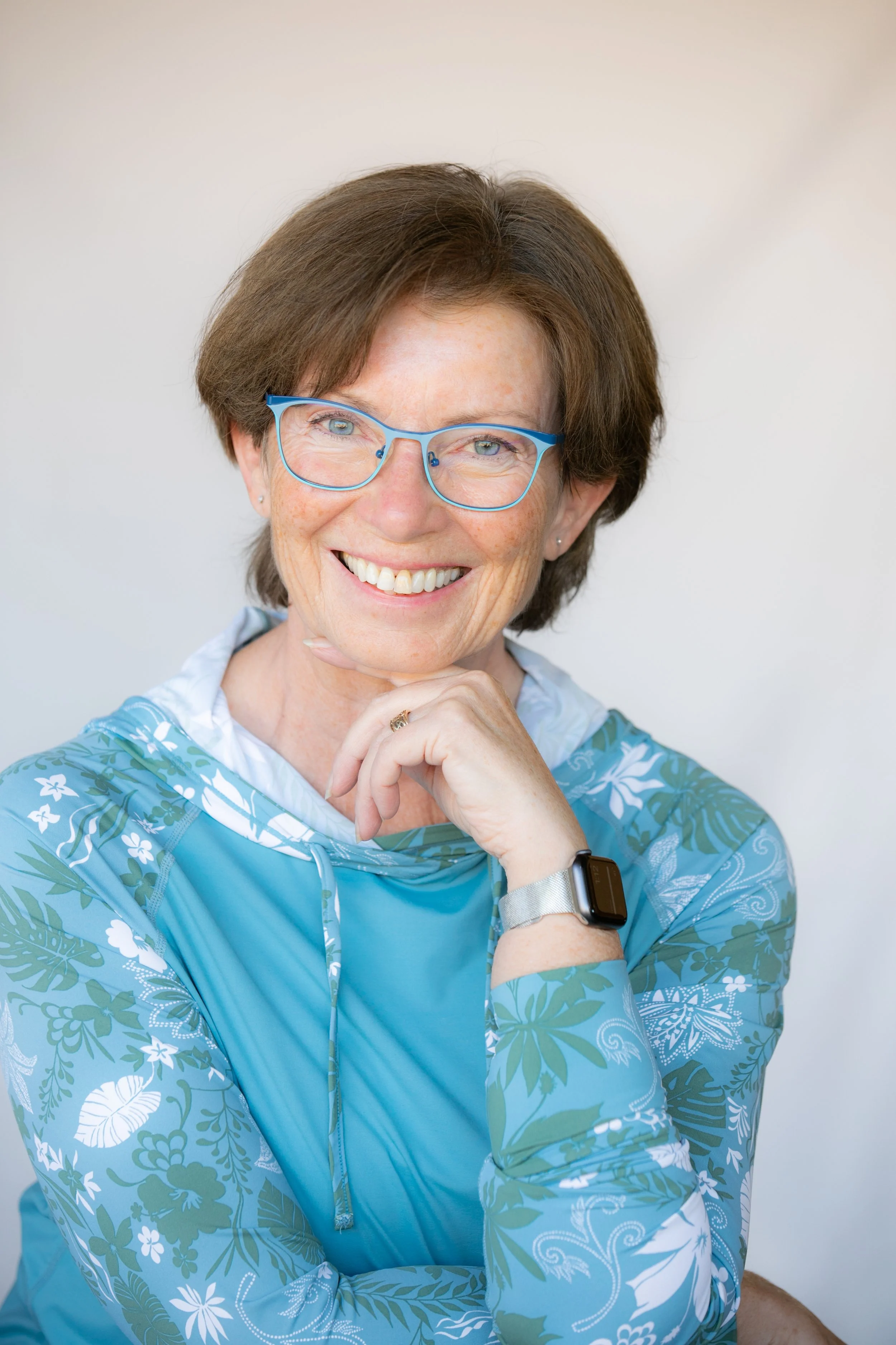 Jackie with blue framed glasses smiling.