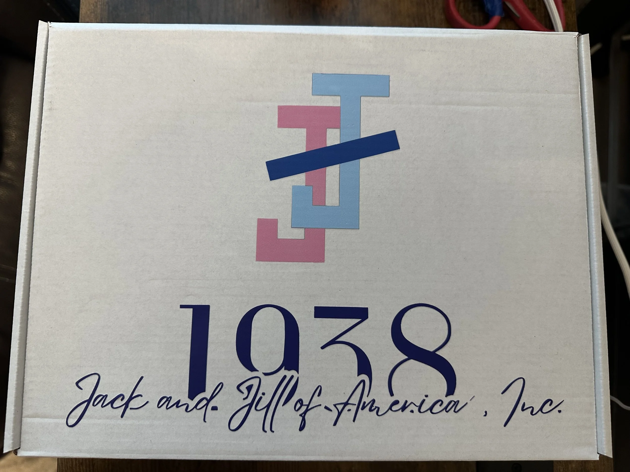 A white box with the logo and text '1038 Jack and Jill of America Inc.' in blue, pink, and light blue lettering.