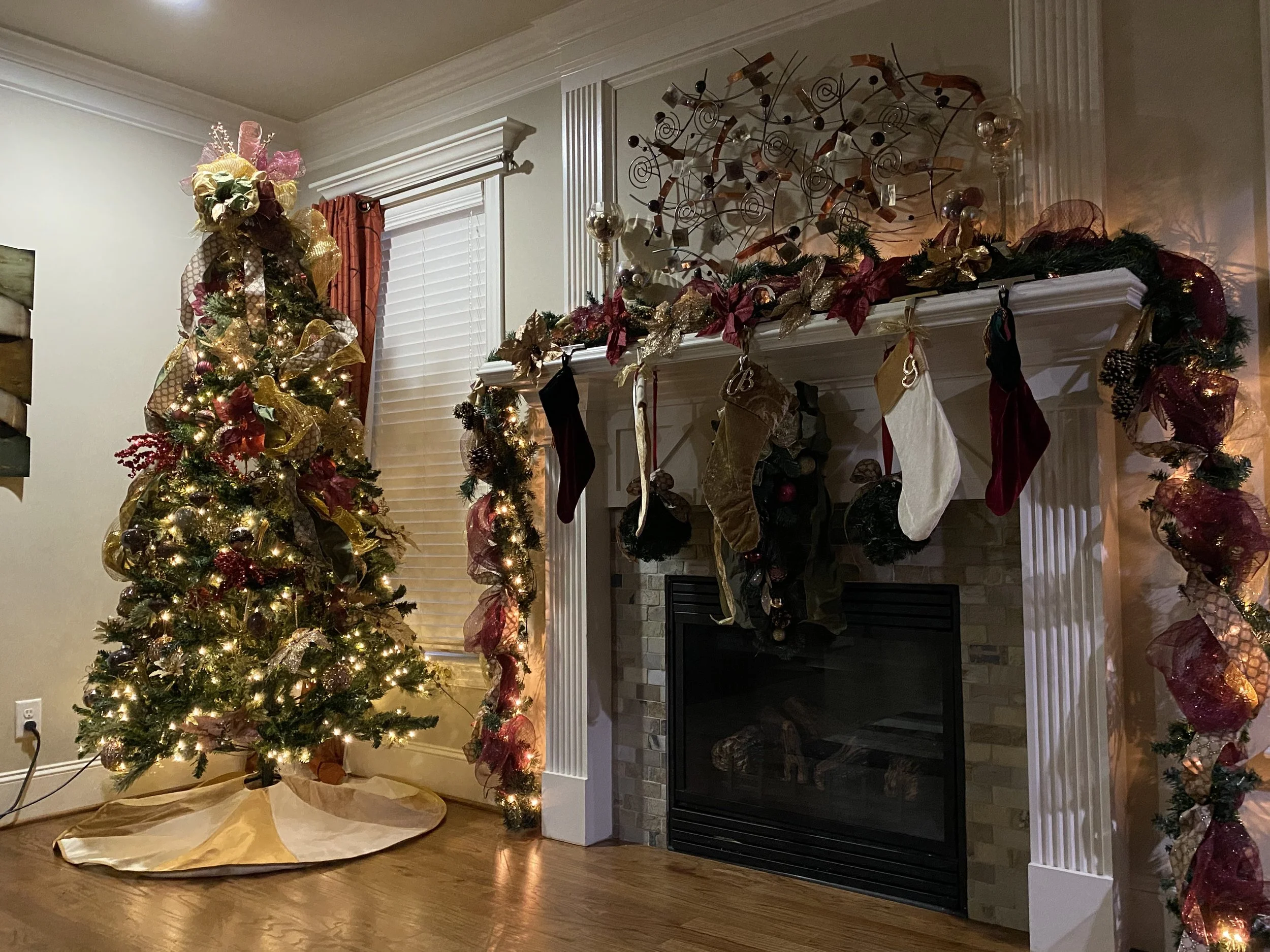 Christmas decorated living room with a lit Christmas tree and a fireplace with stockings hanging, holiday garland, and ornaments.