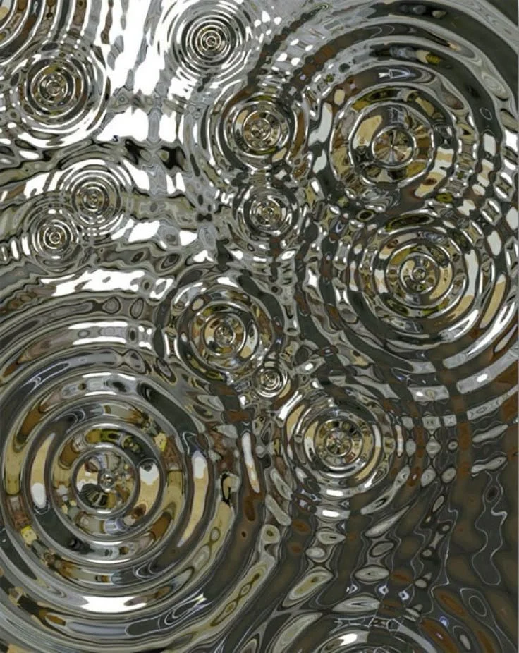 Close-up view of rain droplets creating concentric ripples on the surface of water.