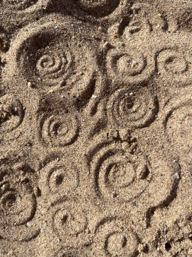 Sand with multiple patterns of spirals and swirls drawn in it.