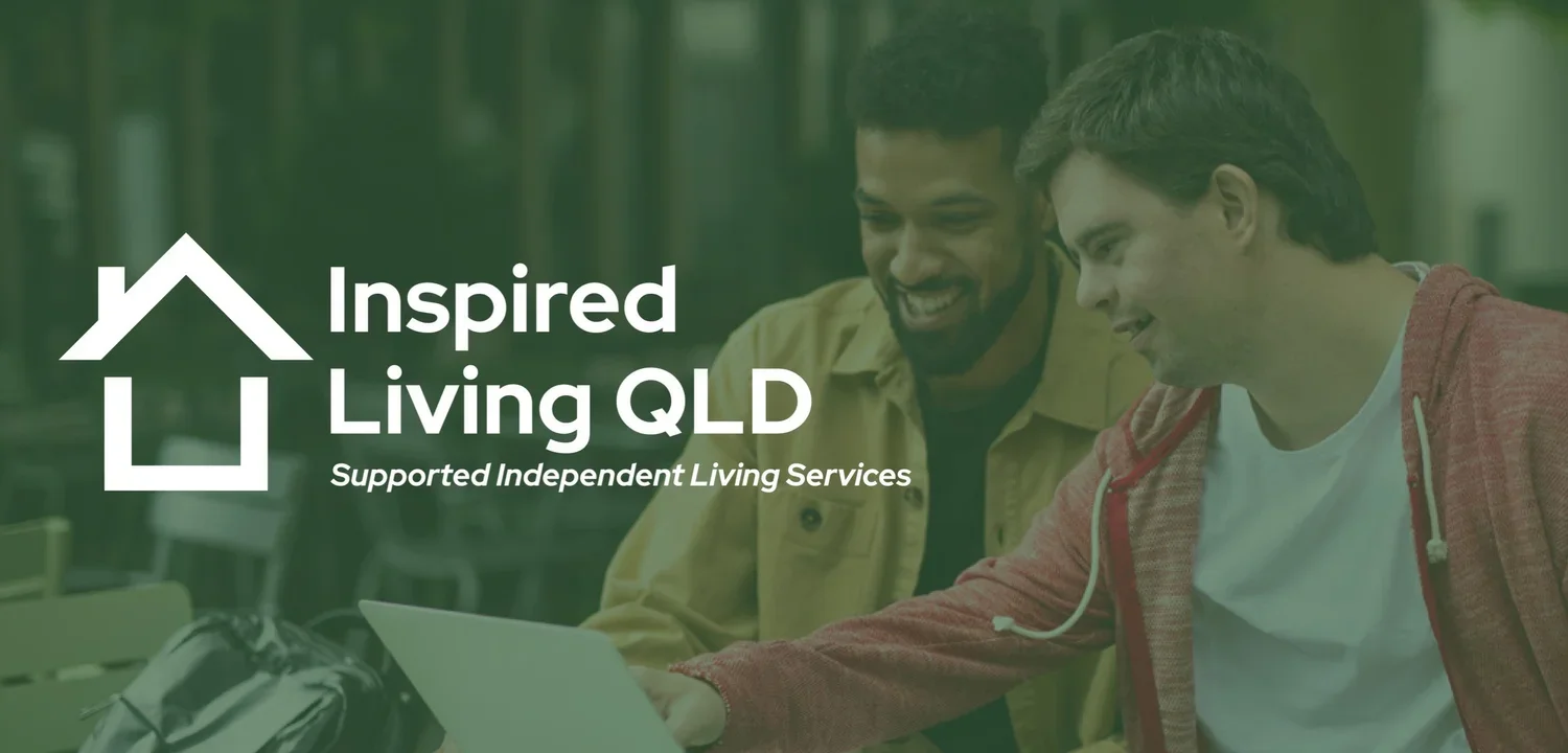 Two men smiling and looking at a laptop, with a backpack nearby, in an indoor setting, overlaid with text reading "Inspired Living QLD" and "Supported Independent Living Services."