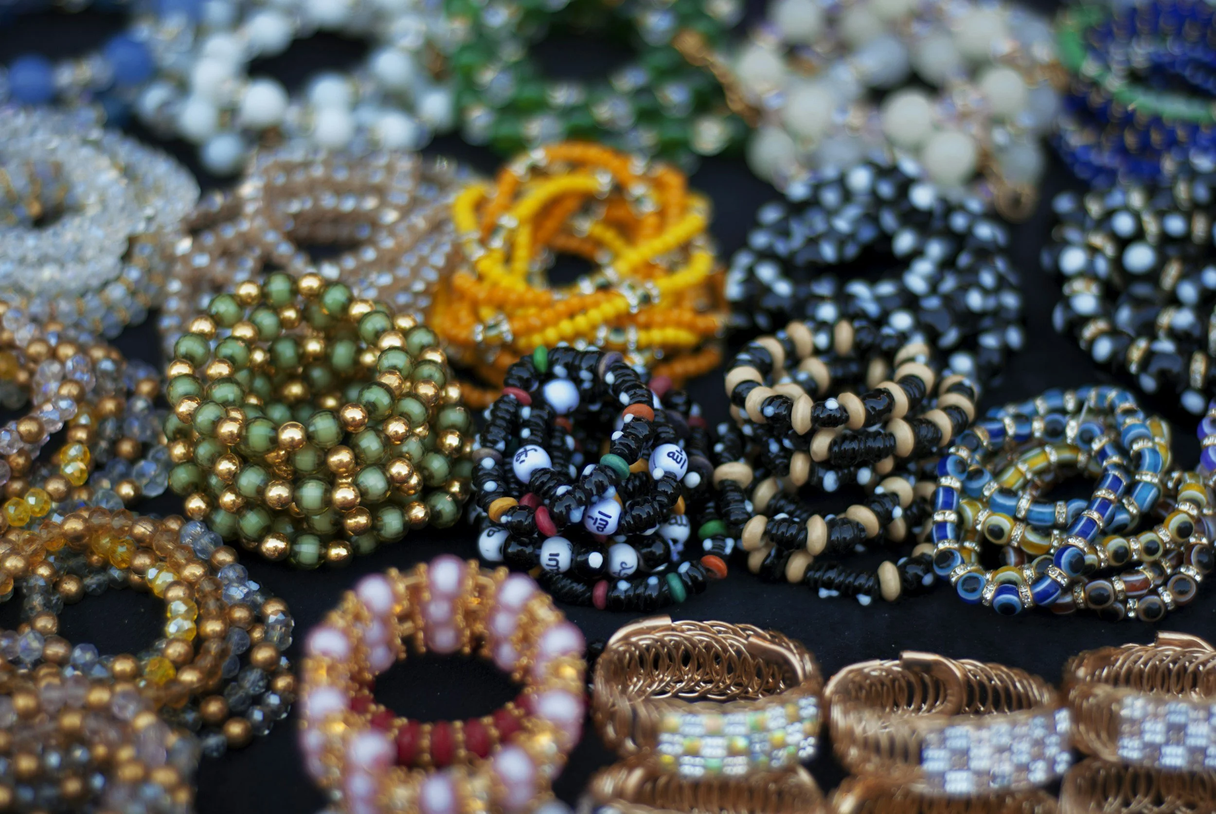 Various colorful beaded bracelets and jewelry displayed on a black surface.