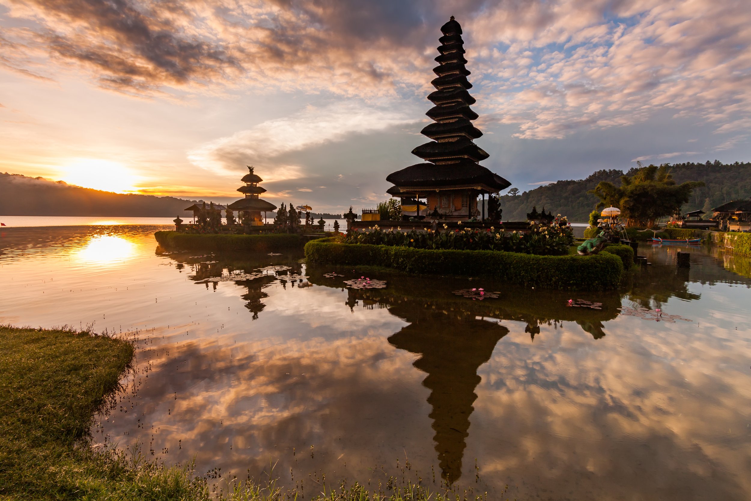 Atardecer en un templo balinés con reflejo en el agua.