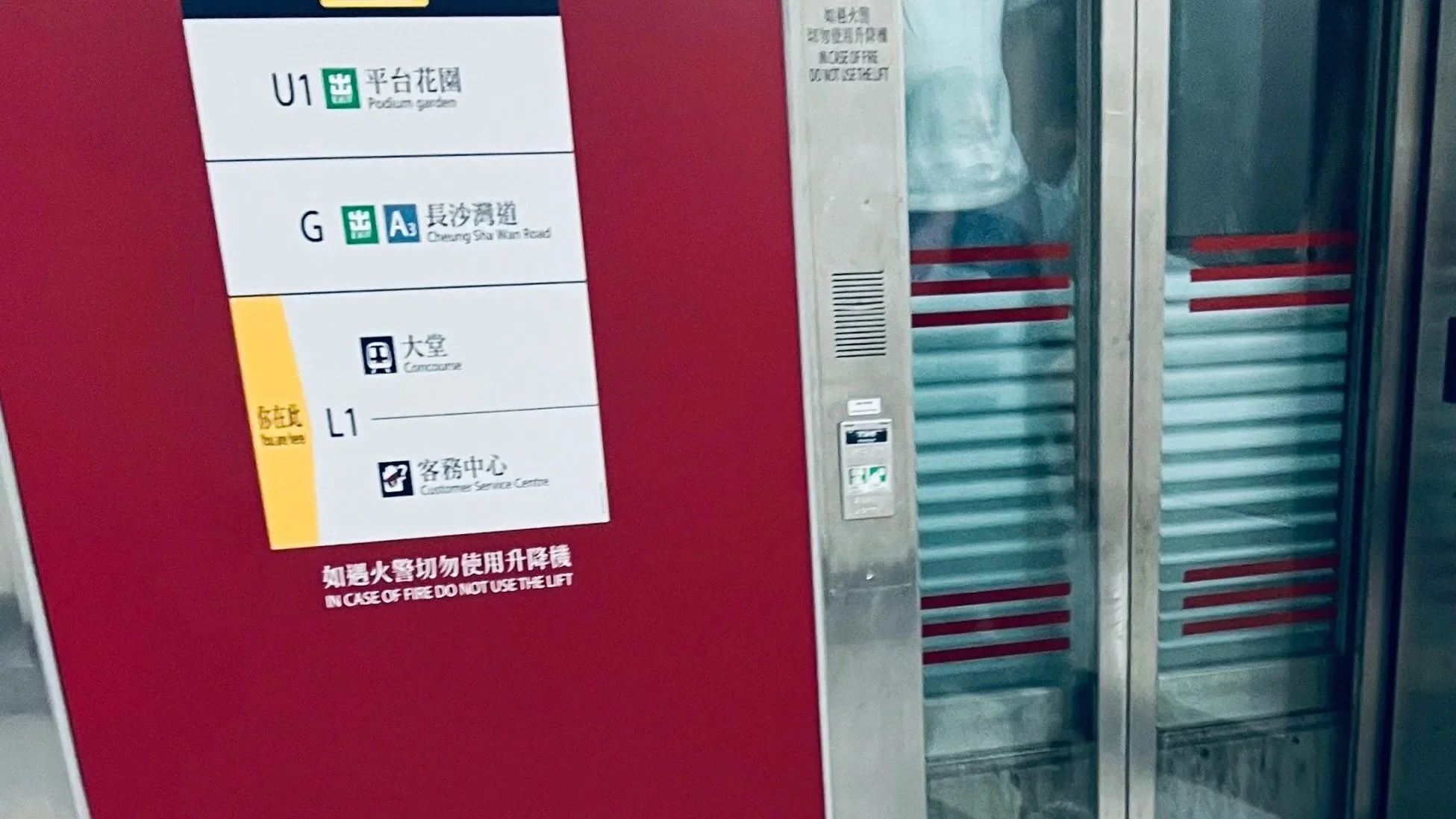 Elevator door with signage showing directions and labels for platforms U1, G, and L1, and instructions in Chinese and English to not use the lift in case of fire.