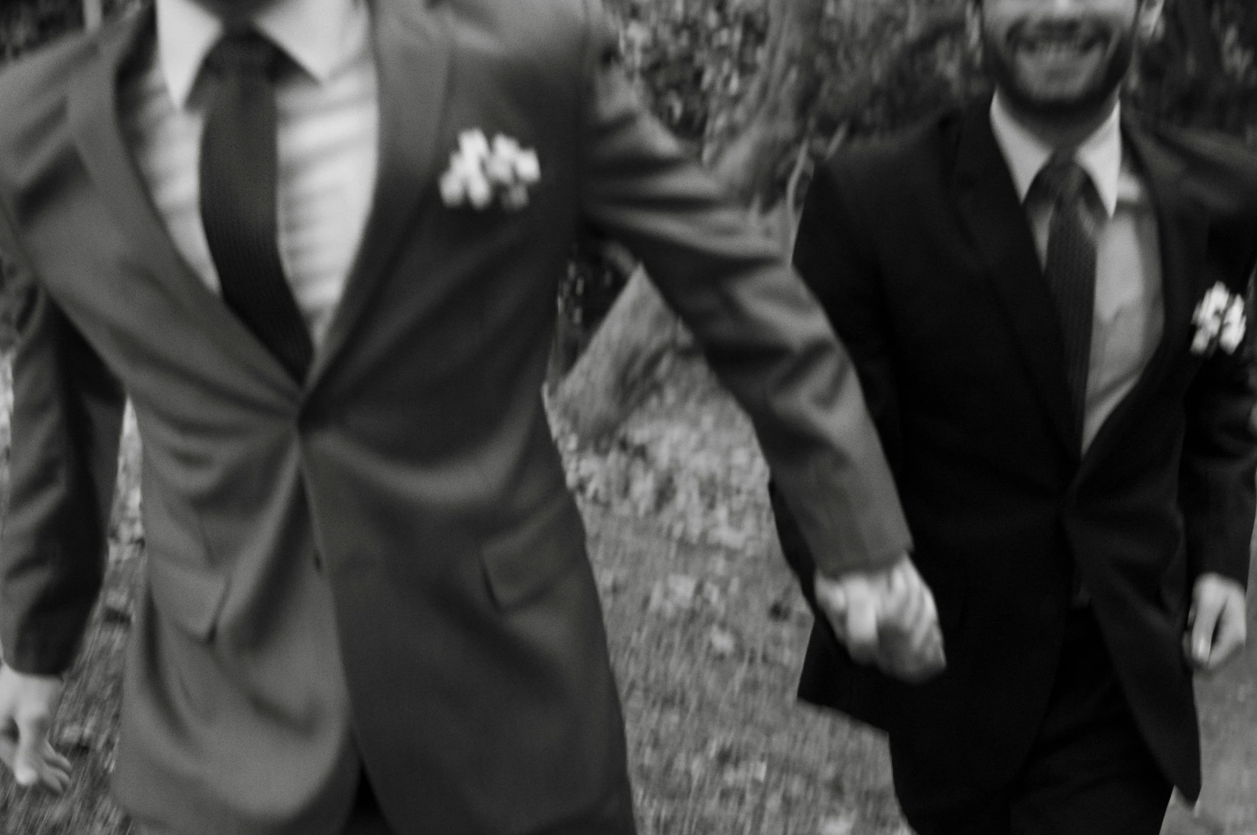 Two men in suits holding hands during a formal event.