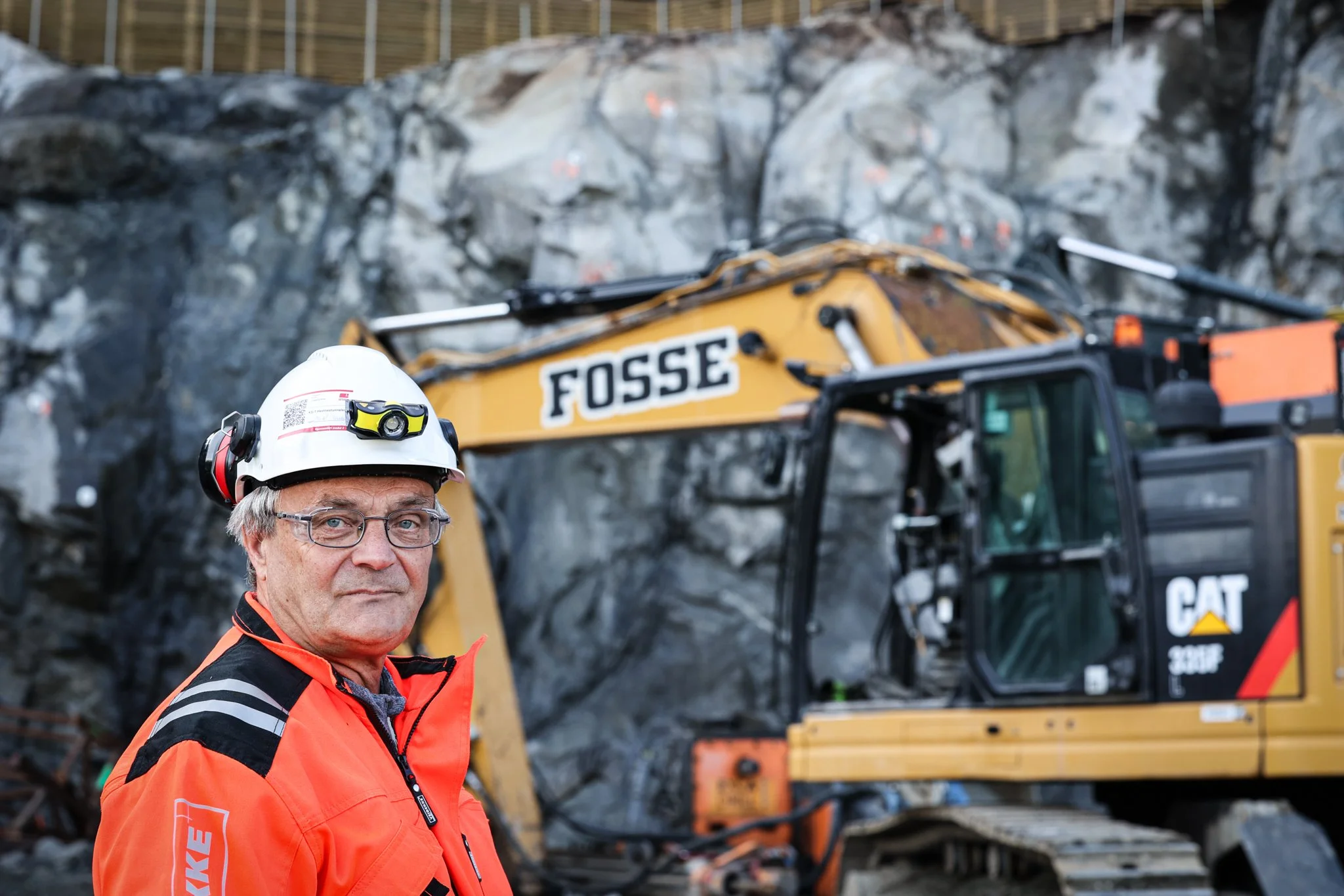 Ole Morten Okkenhaug. Gravemaskin i bakgrunn, Feios
