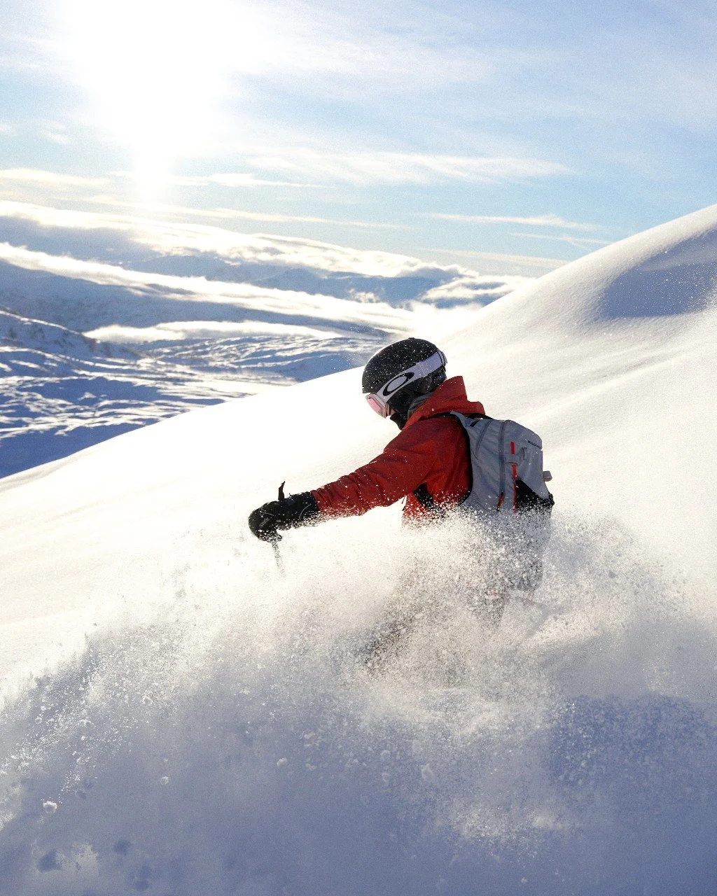 Skikøyrer ned eit fjell i stor fart og med solskinn.