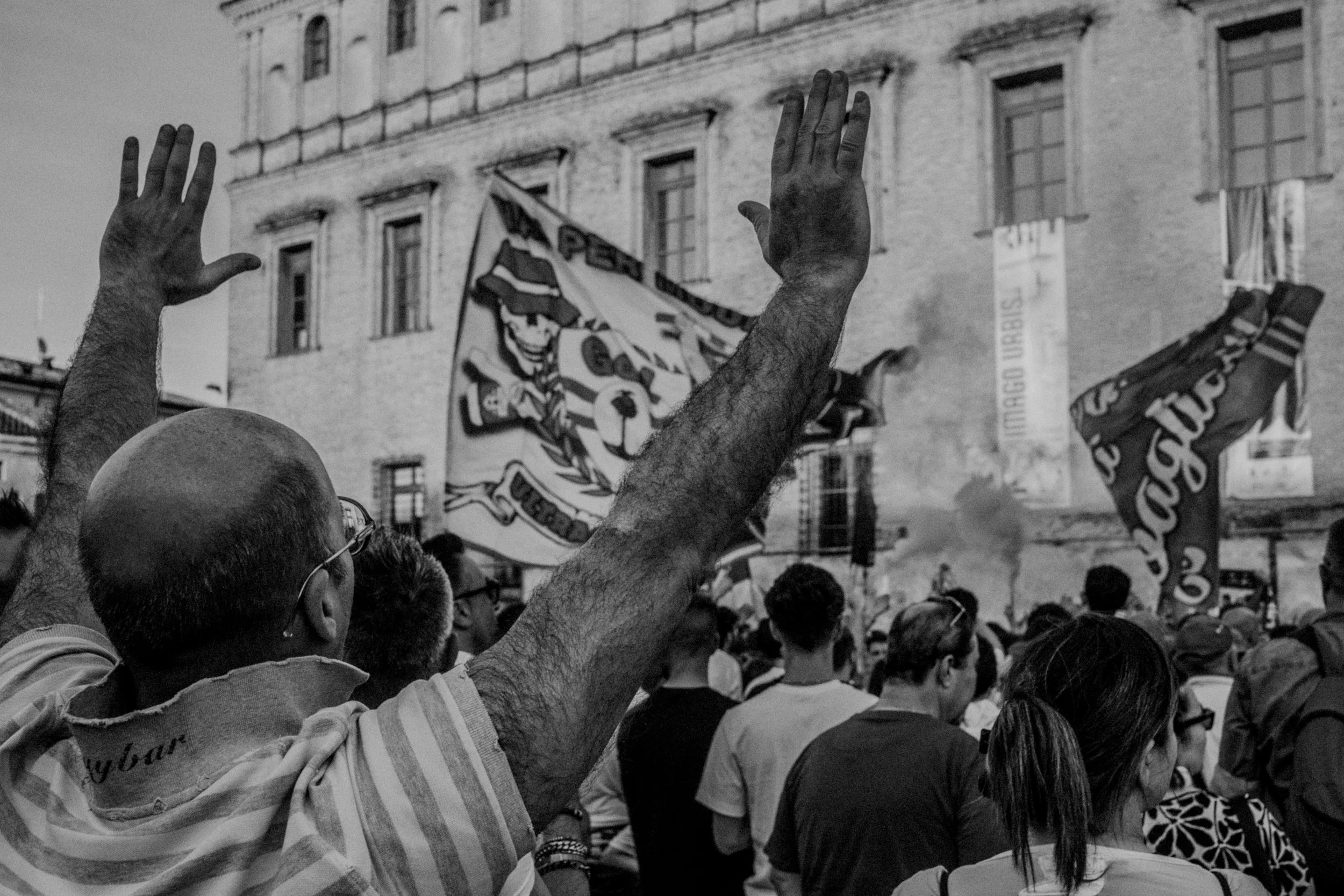 Una protesta di gruppo con persone che alzano le mani, con bandiere.