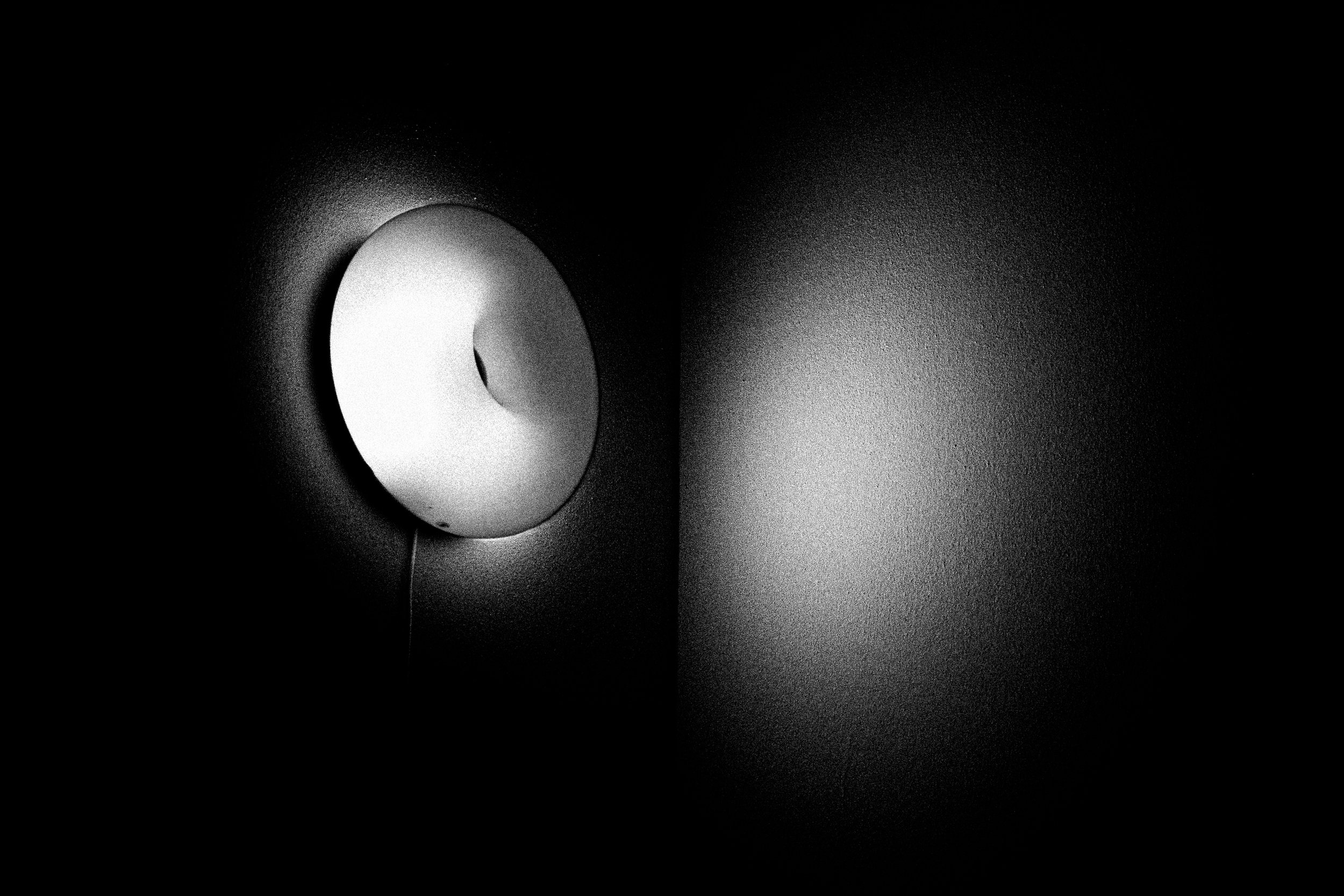 Luce da soffitto accesa in una stanza buia, con barlumi di luce che si riflettono sulle pareti e sul soffitto.