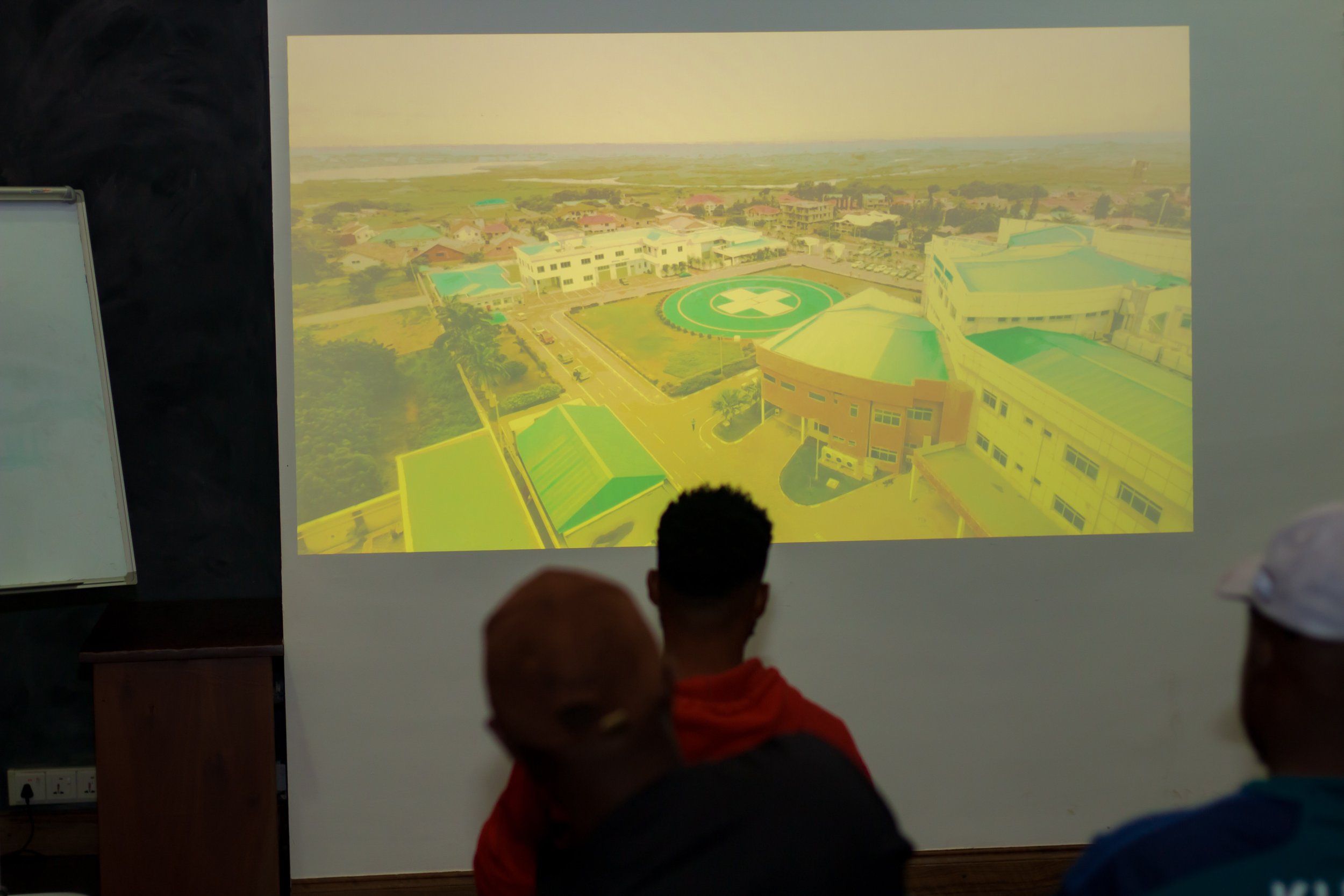 People watching a presentation of a hospital campus projected on a screen.