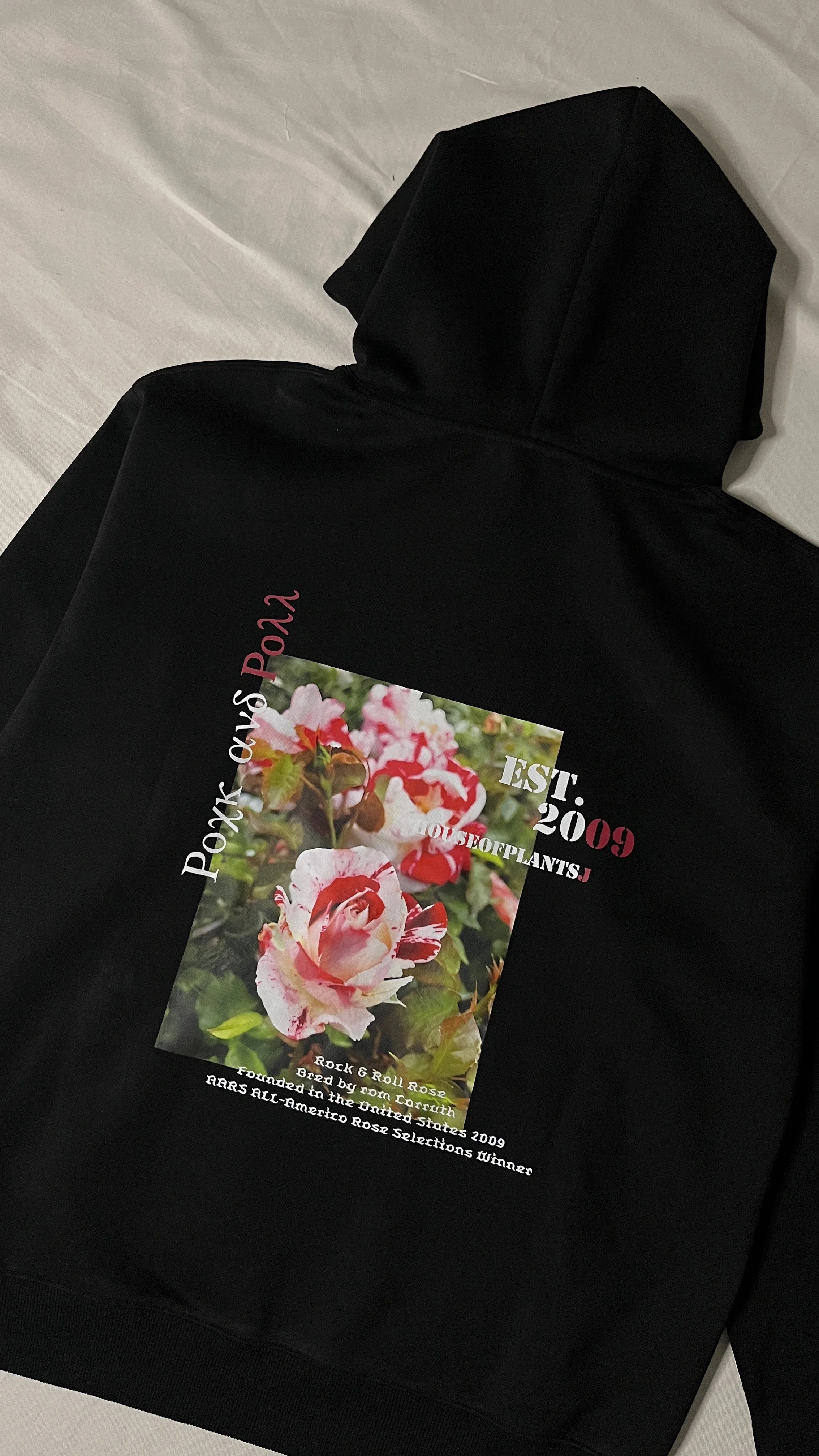 Black hoodie with a printed image of pink and white roses, text about rock and roll roses, established in 2009, grown by Ron Curruth, and winners of the ARRS All-America Rose Selections in 2009.