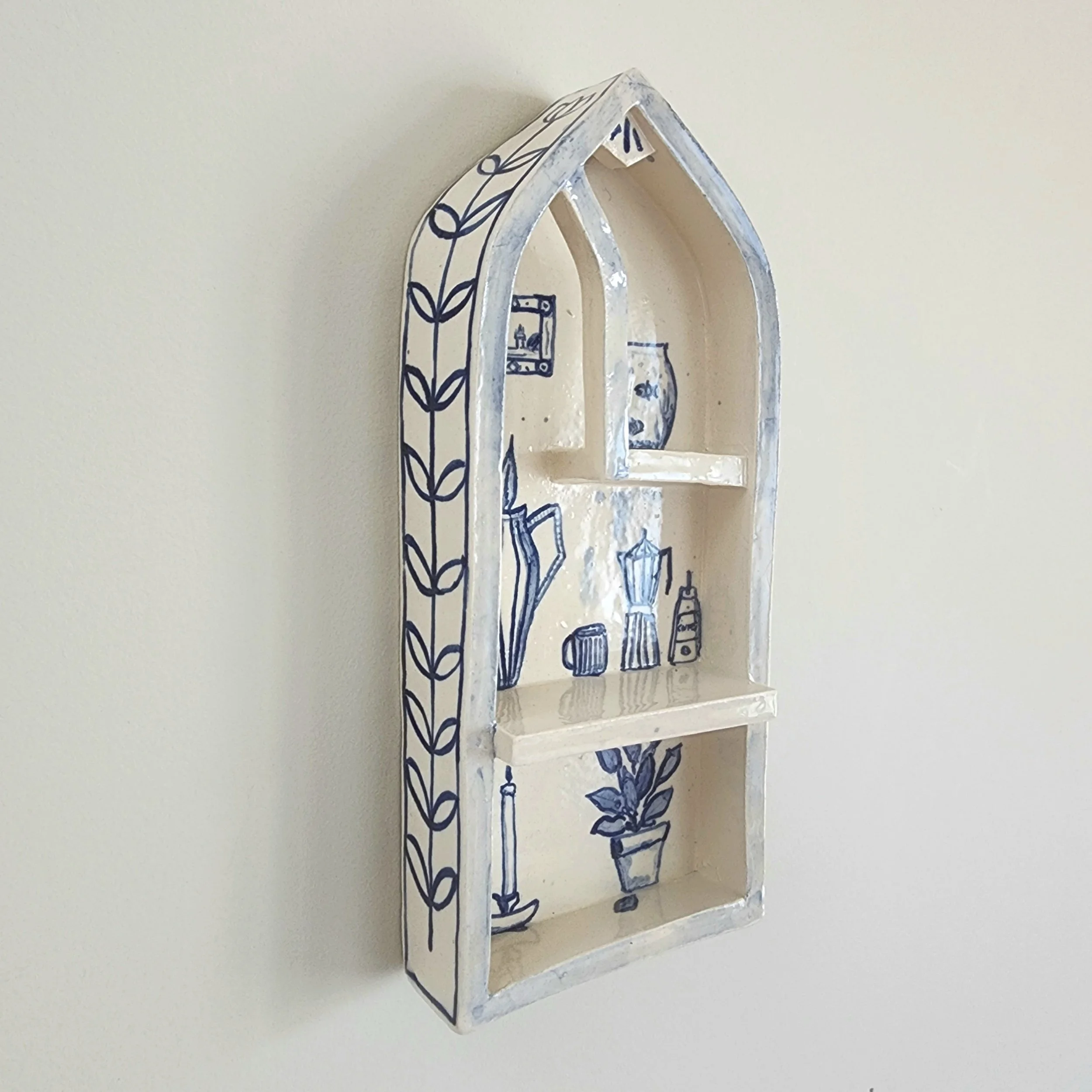 One-off wall hung shrine in stoneware. Hand painted and then glazed. Hangs on a nail. 

The illustrations are inspired by the comforts of a home that is safe and cocooning. 

Can be used to display small trinket, or just hang as is. 

Measurements:
H
