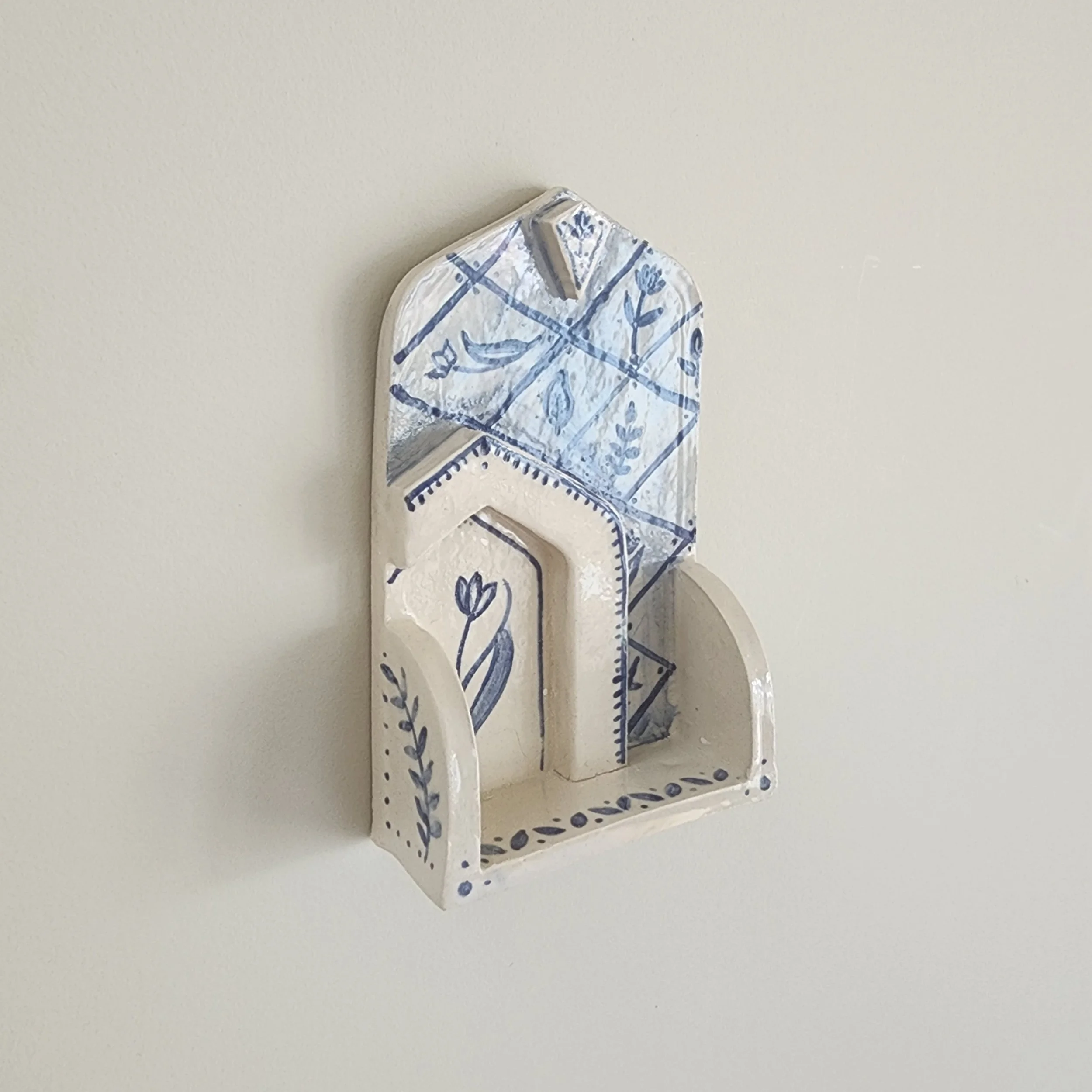 One-off wall hung shrine in stoneware. Hand painted and then glazed. Hangs on a nail. 

The botanical illustrations and shape are inspired travels to places that I have a special connection with. 

Can be used to display small trinket, or just hang a