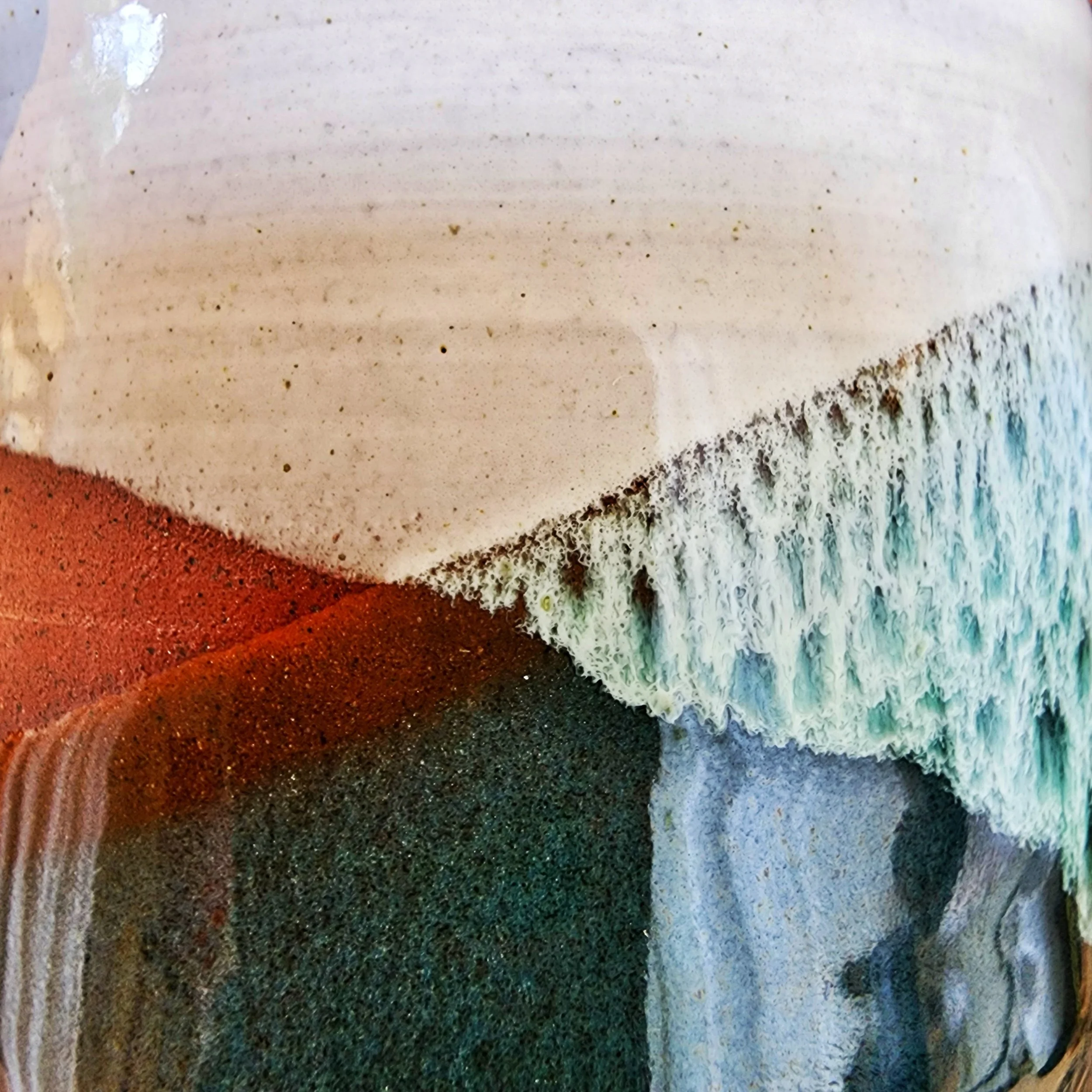 Close-up of green and white glaze on terracotta mug