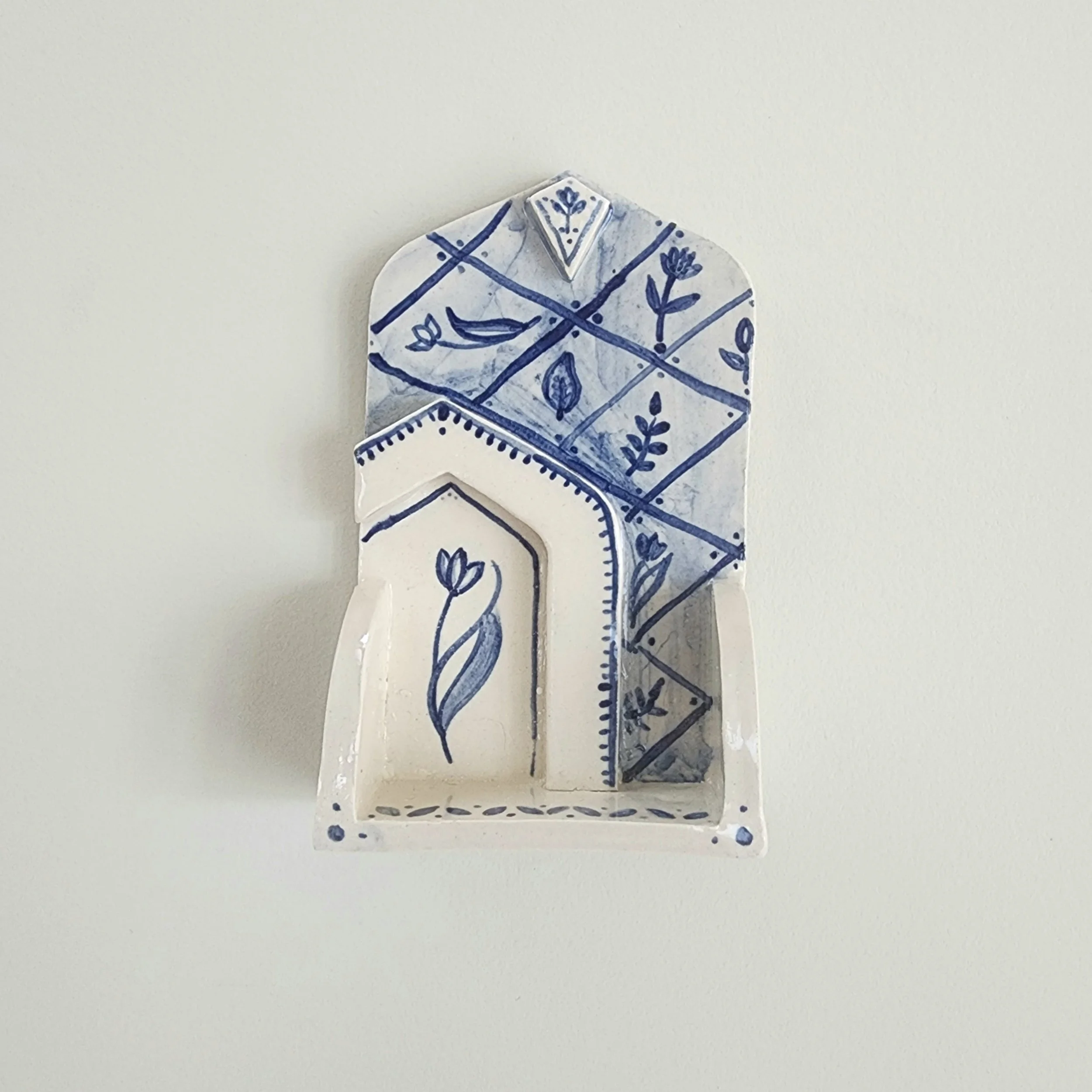 One-off wall hung shrine in stoneware. Hand painted and then glazed. Hangs on a nail. 

The botanical illustrations and shape are inspired travels to places that I have a special connection with. 

Can be used to display small trinket, or just hang a
