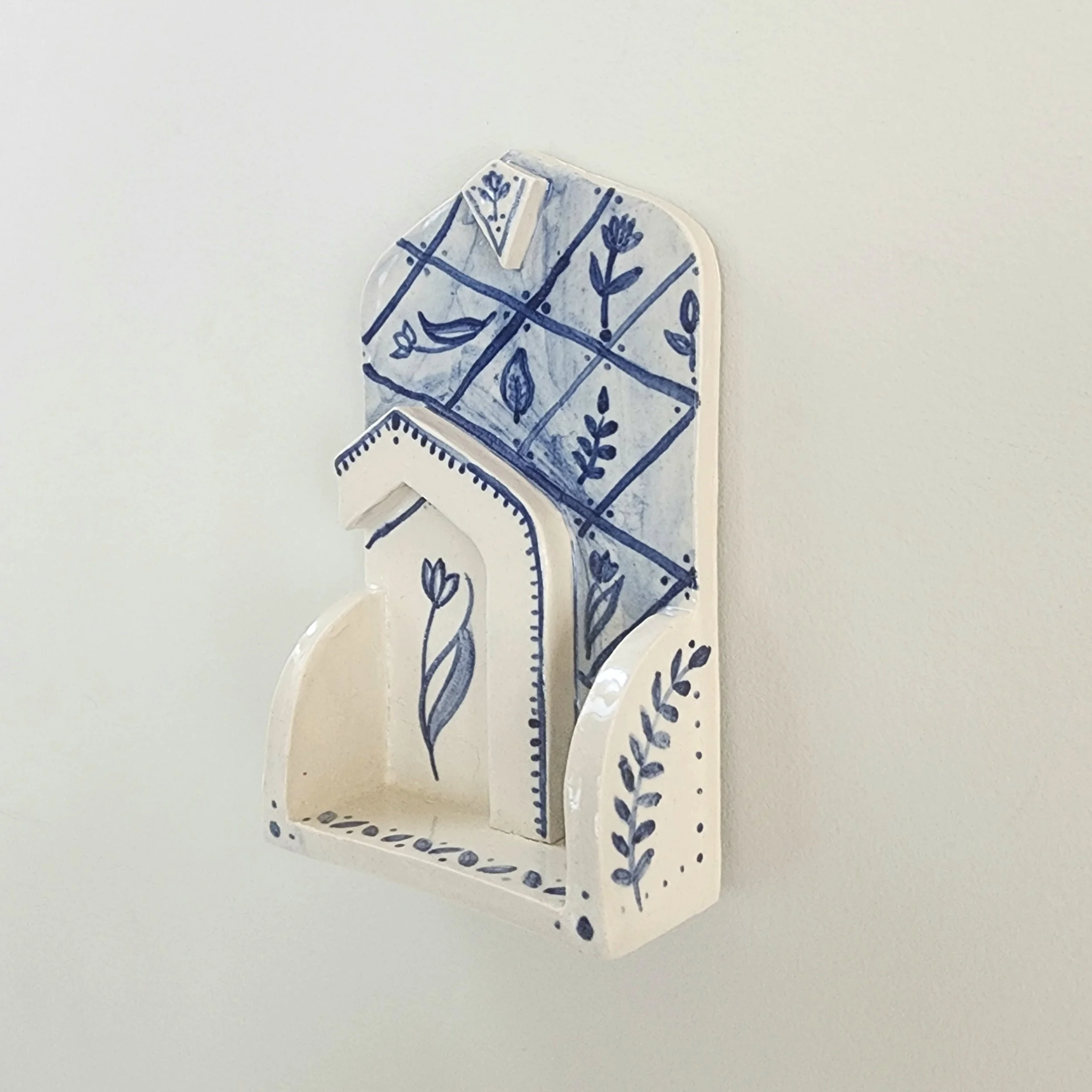 One-off wall hung shrine in stoneware. Hand painted and then glazed. Hangs on a nail. 

The botanical illustrations and shape are inspired travels to places that I have a special connection with. 

Can be used to display small trinket, or just hang a