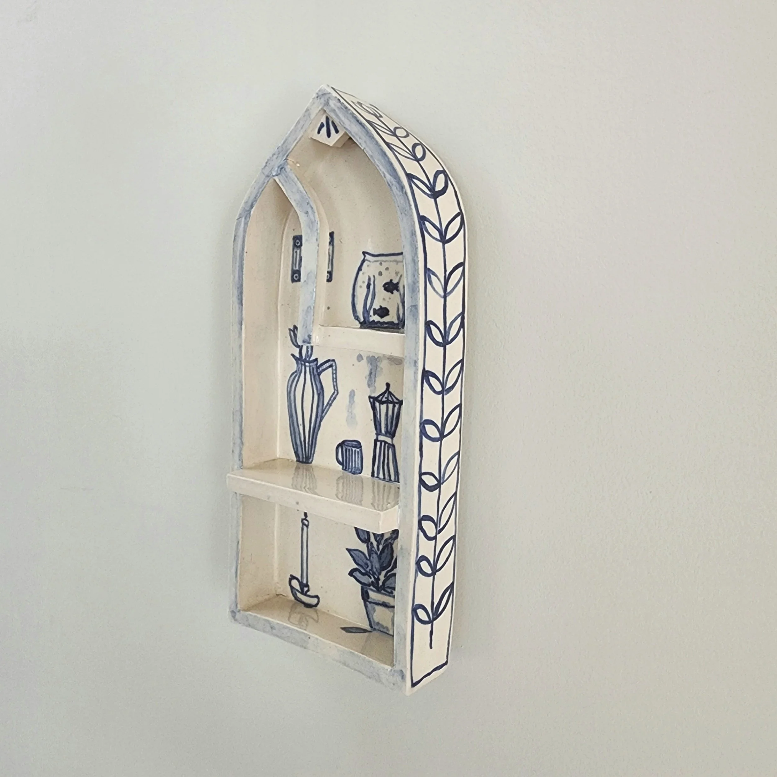 One-off wall hung shrine in stoneware. Hand painted and then glazed. Hangs on a nail. 

The illustrations are inspired by the comforts of a home that is safe and cocooning. 

Can be used to display small trinket, or just hang as is. 

Measurements:
H