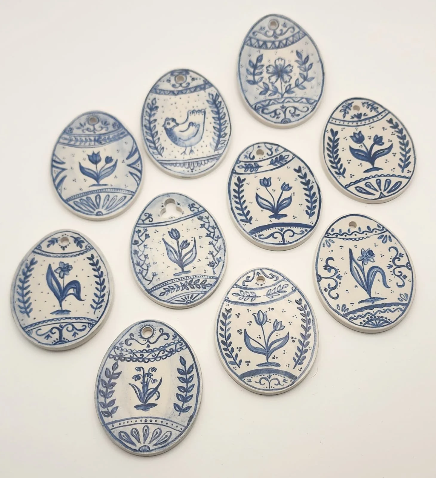 Ceramic Easter eggs with blue floral and bird patterns on a white background