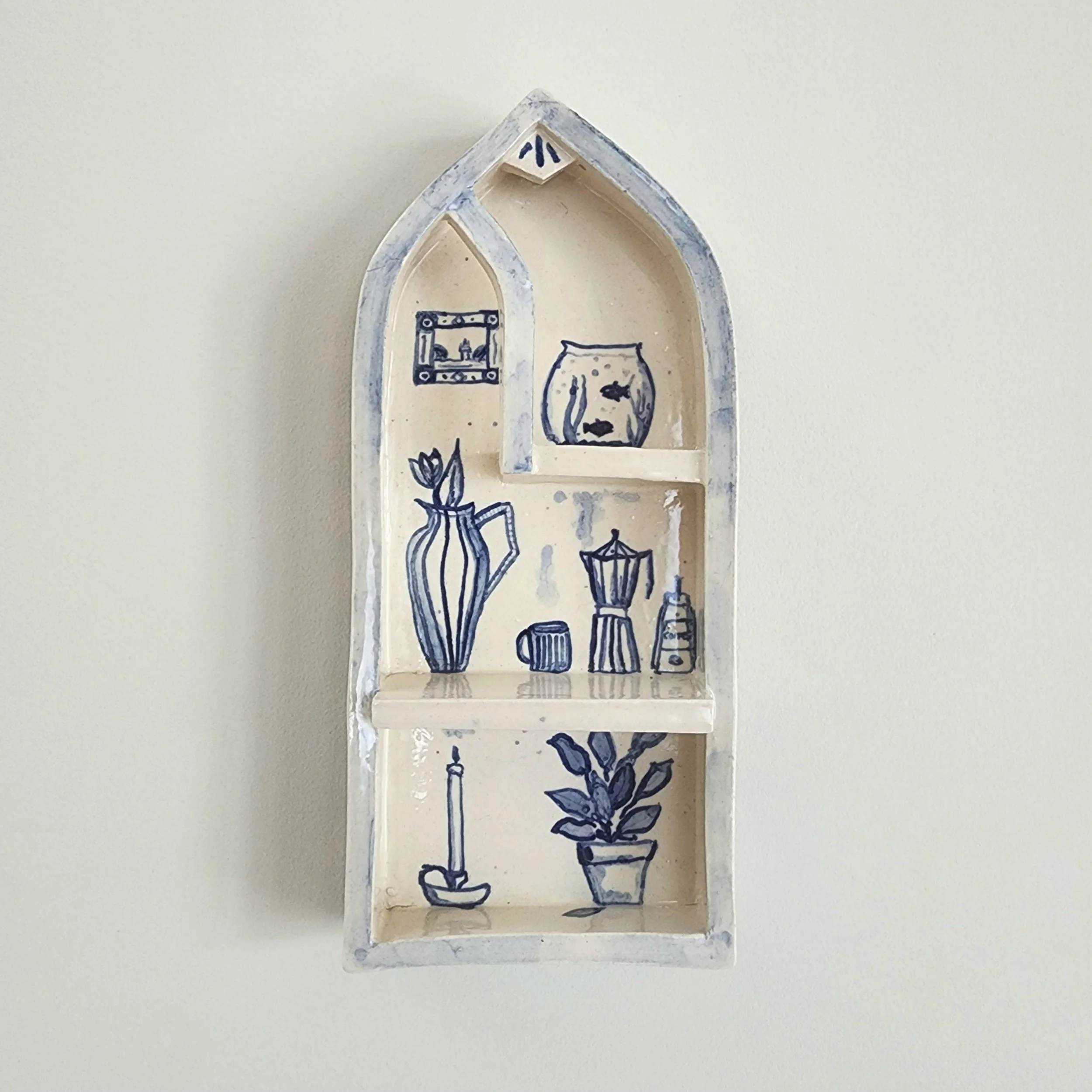 One-off wall hung shrine in stoneware. Hand painted and then glazed. Hangs on a nail. 

The illustrations are inspired by the comforts of a home that is safe and cocooning. 

Can be used to display small trinket, or just hang as is. 

Measurements:
H