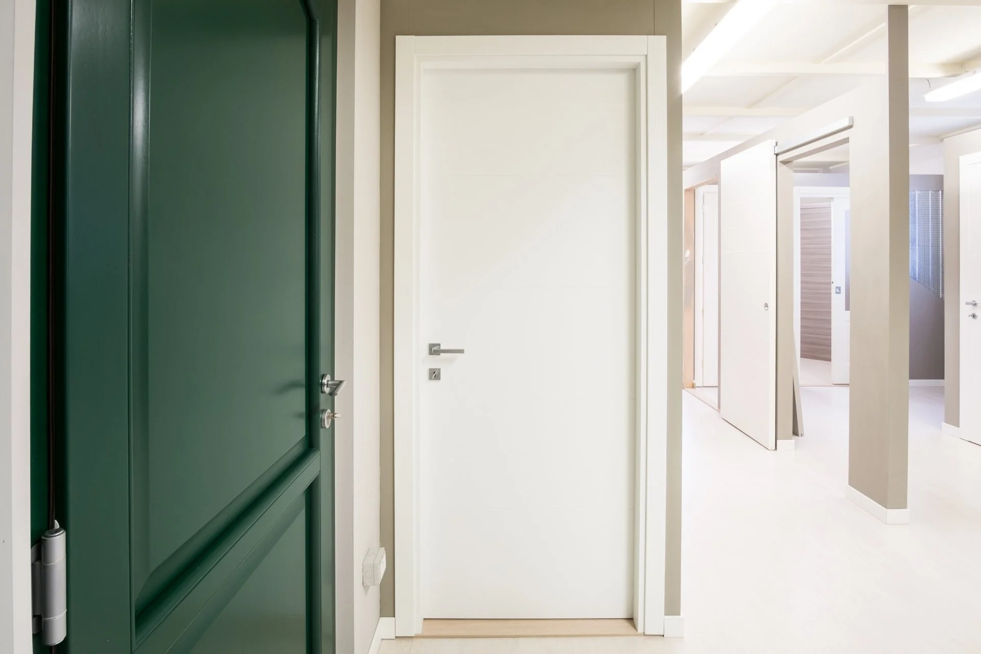 Ingresso di un edificio con porte bianche e una porta verde