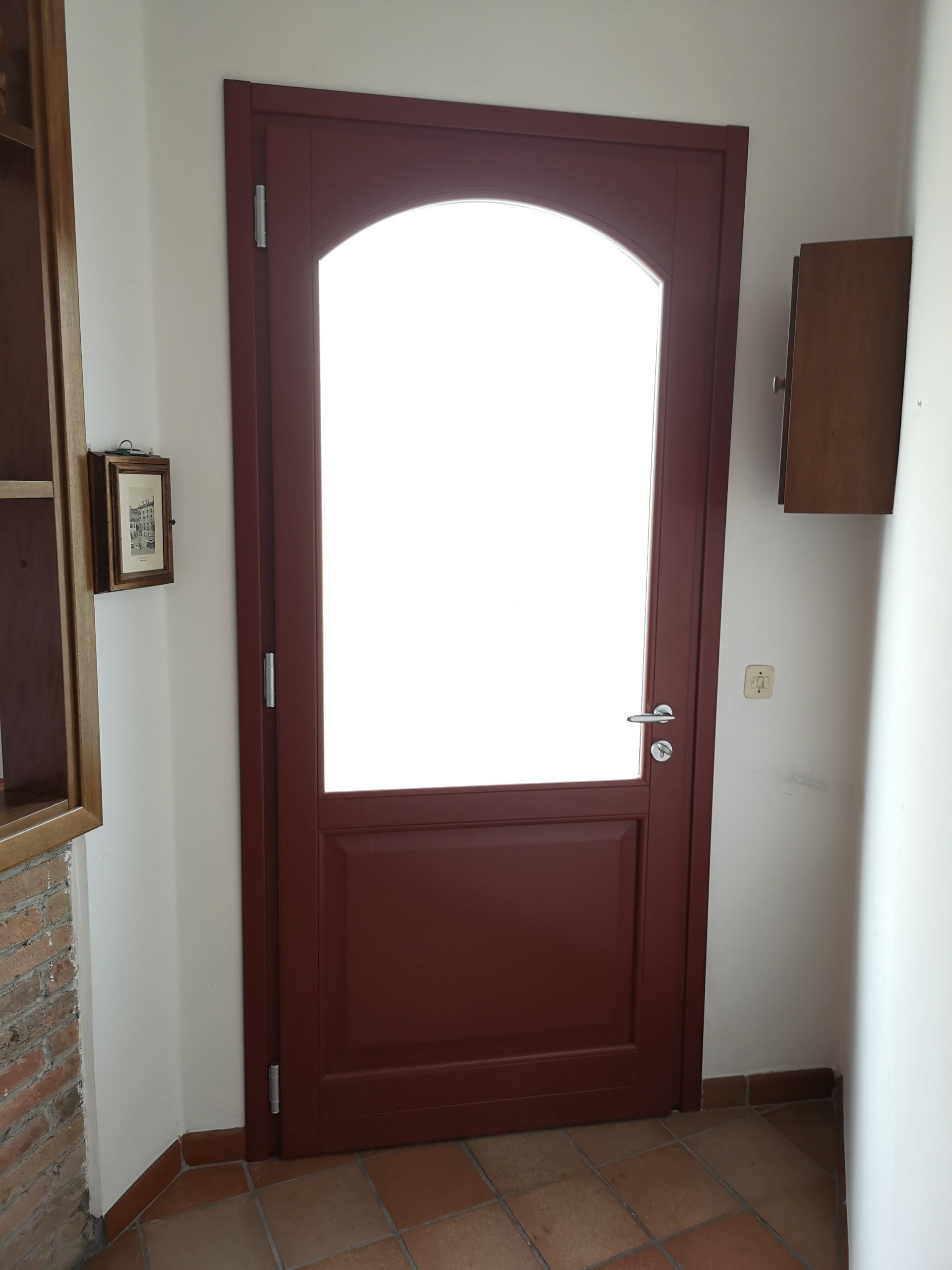 porta di legno rossa con vetro satinato nella parte superiore, chiusa, in un ingresso o corridoio