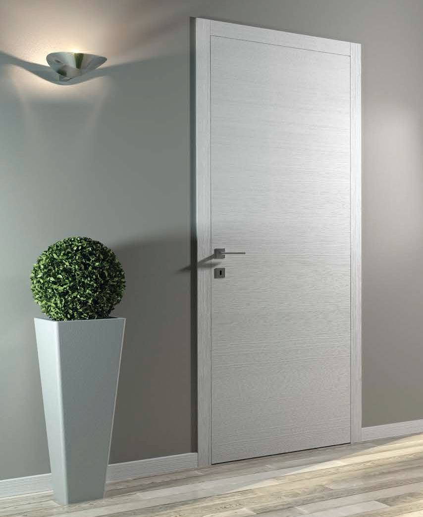 Porta bianca moderna in un interno con pareti grigie, lampada da parete in alto a sinistra e pianta verde in un vaso bianco a sinistra.