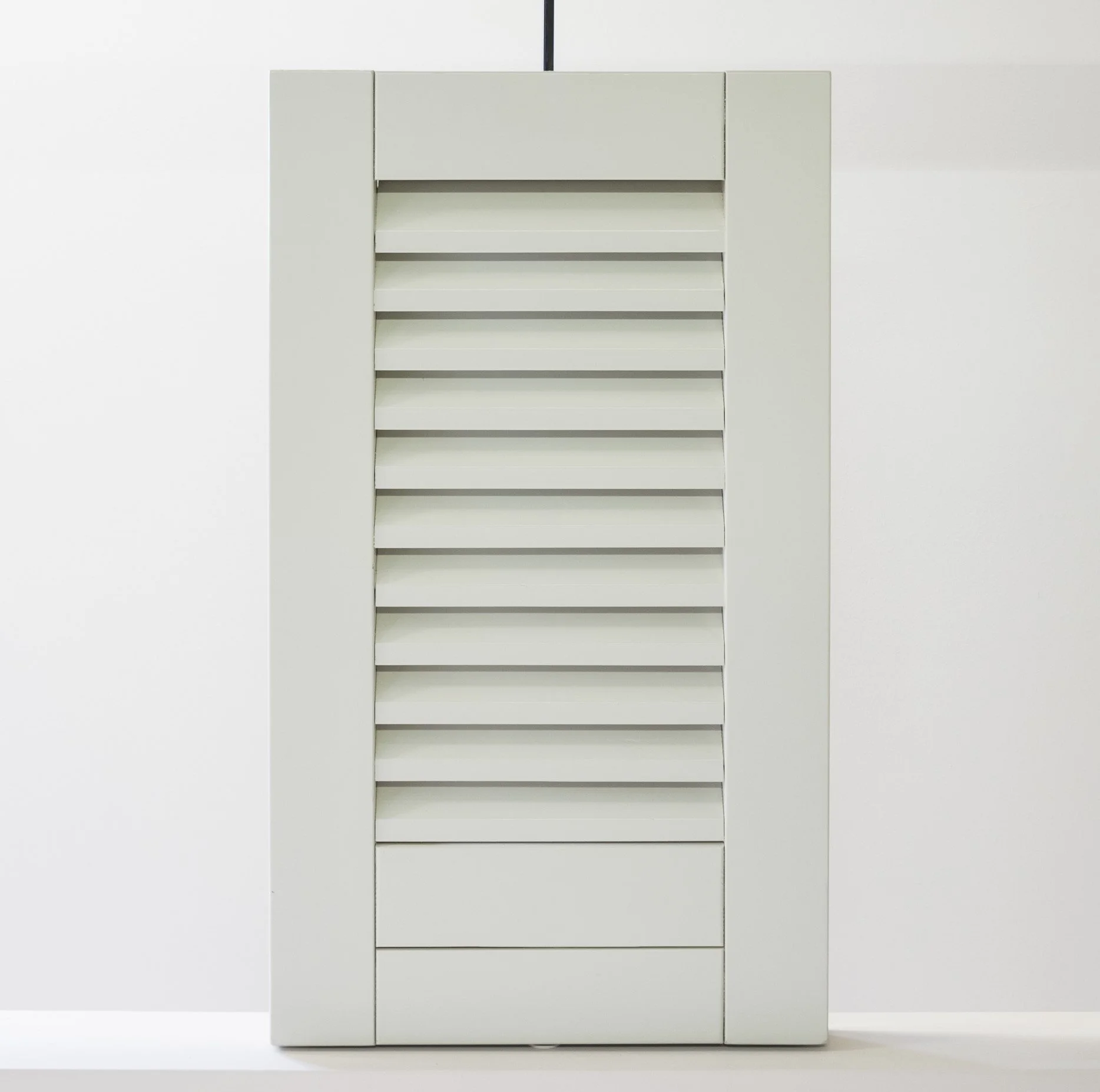 Mobiletto bianco con porte a lamelle.