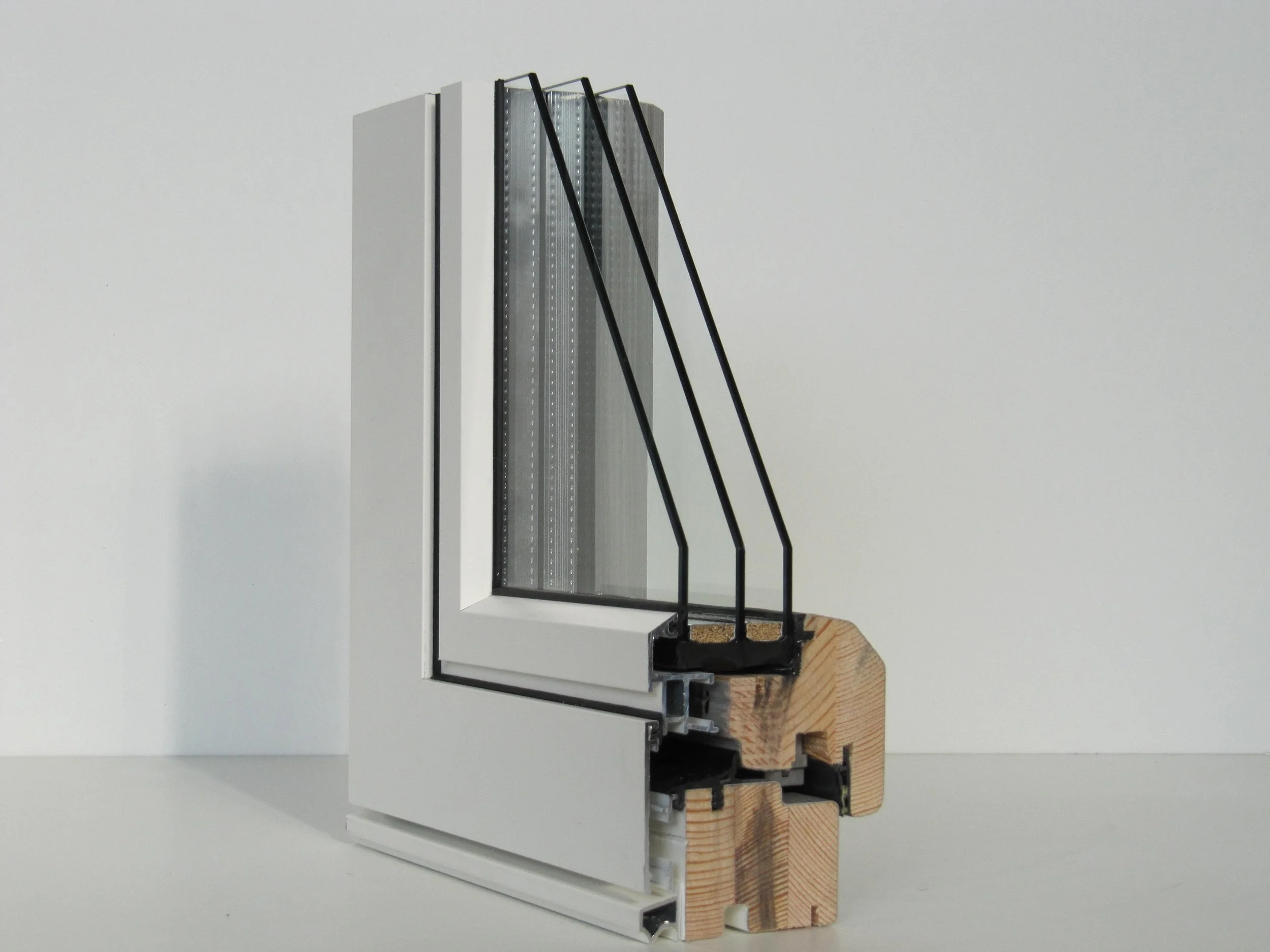 Sezione di una finestra con doppi vetri, profilatura bianca, telaio in legno e struttura in alluminio.