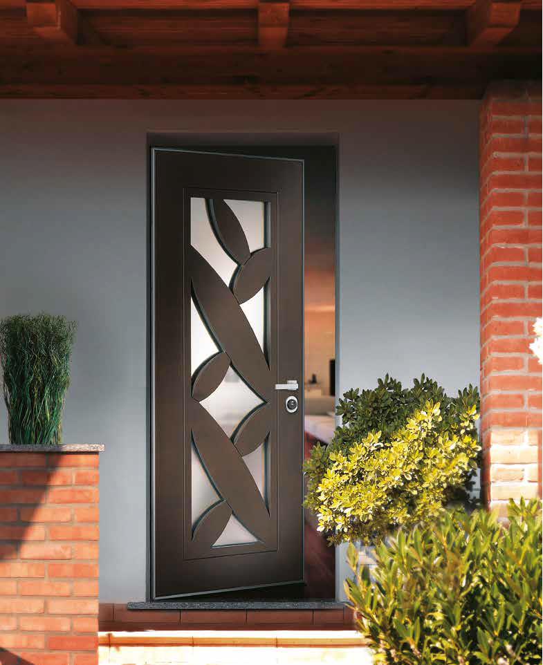 Porta d'ingresso moderna con motivo decorativo in vetro e dettagli in legno, circondata da piante verdi.