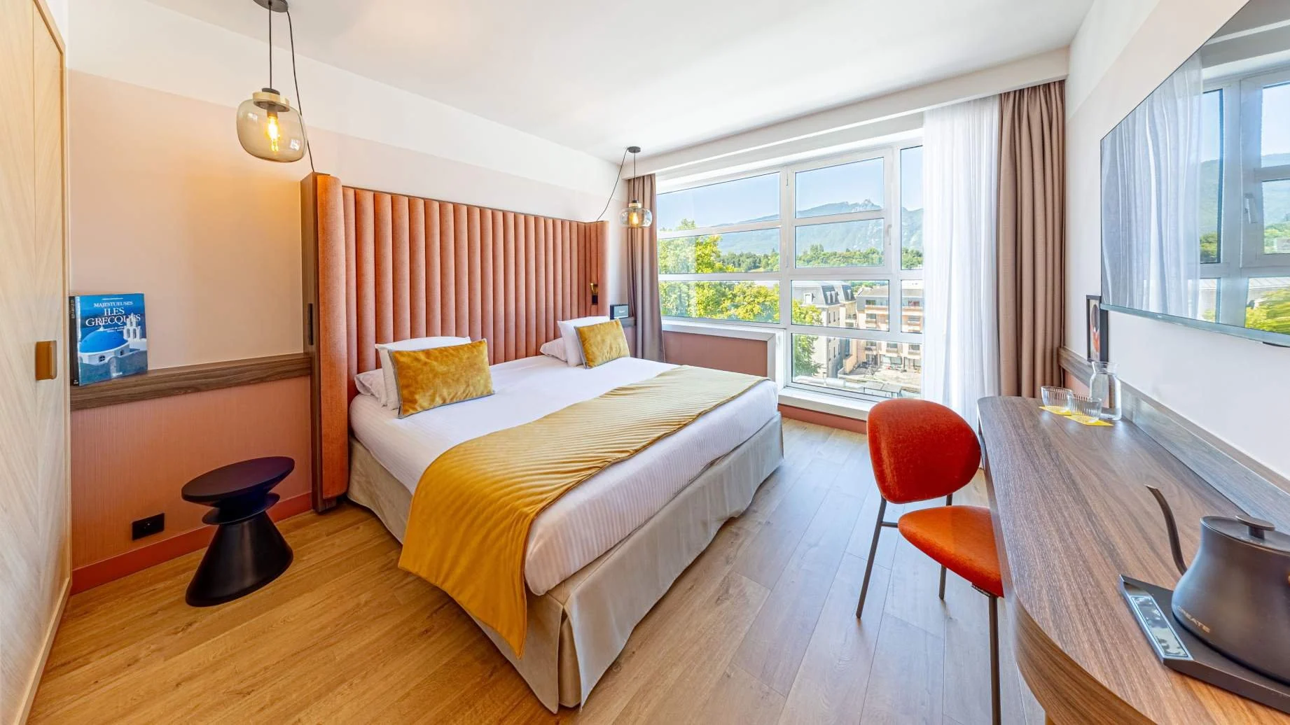 Chambre moderne et lumineuse de l’hôtel Golden Tulip, avec un lit confortable et de grandes fenêtres.