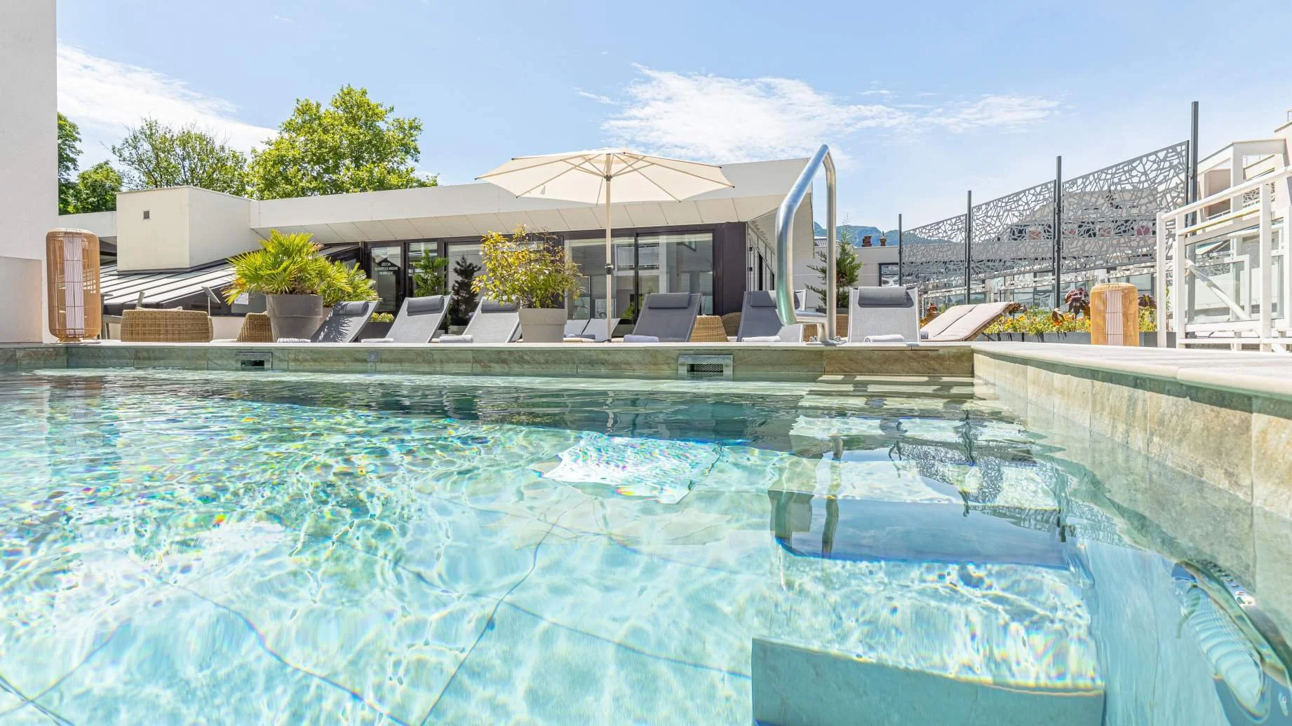 Piscina exterior del Hotel Golden Tulip en Aix-les-Bains, rodeada de tumbonas para el relax.