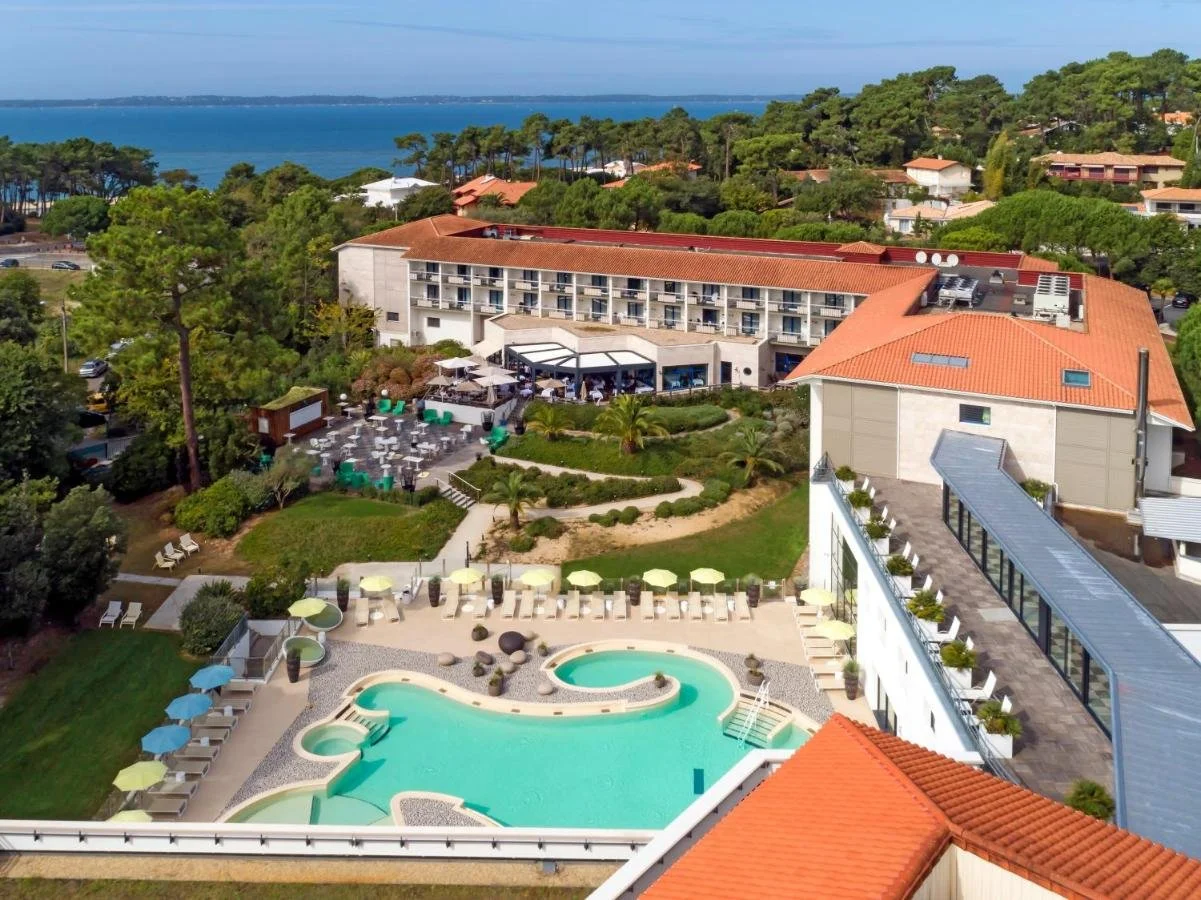 Vue aérienne de l’Hôtel Les Bains d’Arguin à Arcachon, avec une grande piscine type lagon et de vastes jardins, idéal pour des retraites d’entreprise.