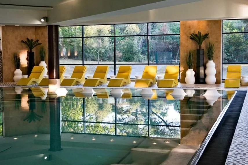 Espace piscine intérieure et détente de l’Hôtel Les Bains d’Arguin, avec un design moderne et des chaises longues,