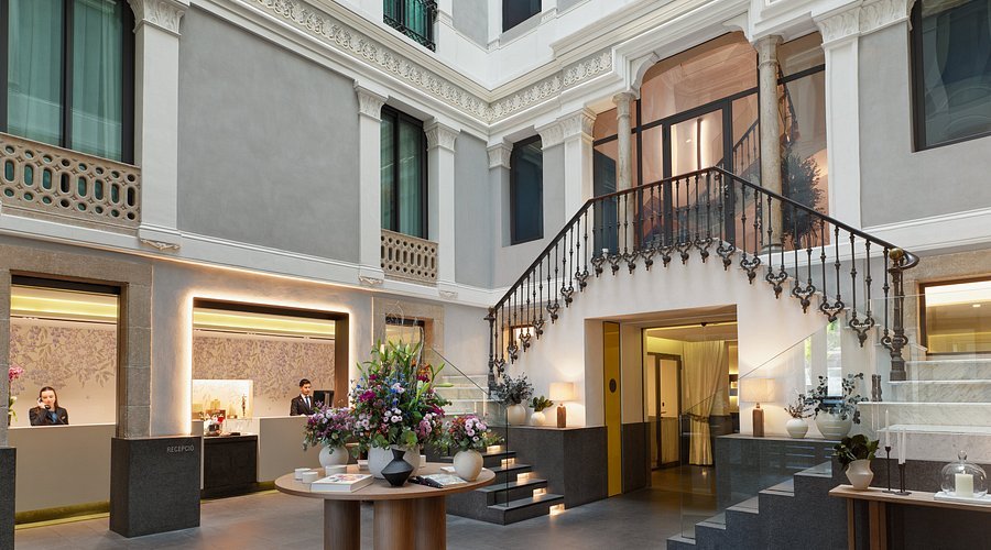 Élégant lobby de l’Hôtel Urquinaona Plaza à Barcelone, avec escalier historique, idéal pour un accueil luxueux lors d’événements d’entreprise.