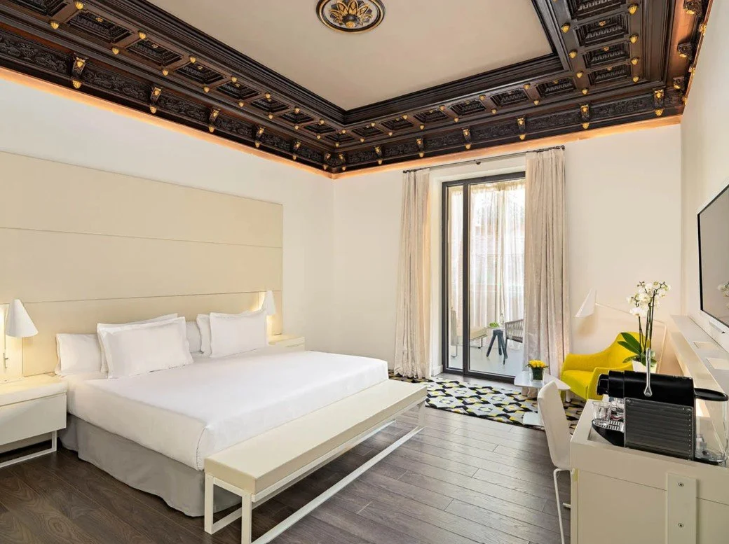 Chambre de luxe avec grand lit et design moderne de l’Hôtel Urquinaona Plaza, idéal pour les voyages d’incentive et de détente.