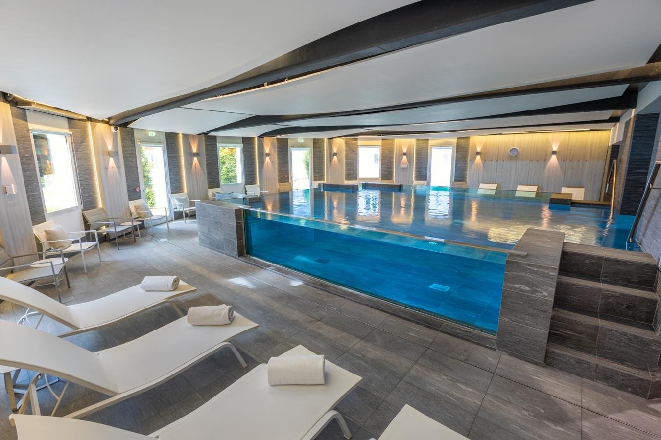 Piscine intérieure de l’Hôtel Imperial Palace avec transats, un espace idéal pour la détente et le bien-être.