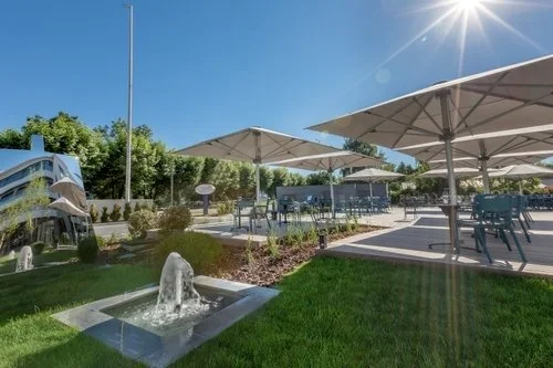 Terrasse extérieure de l’Hôtel Rivage à Annecy avec parasols et chaises longues, idéale pour se détendre après un événement.