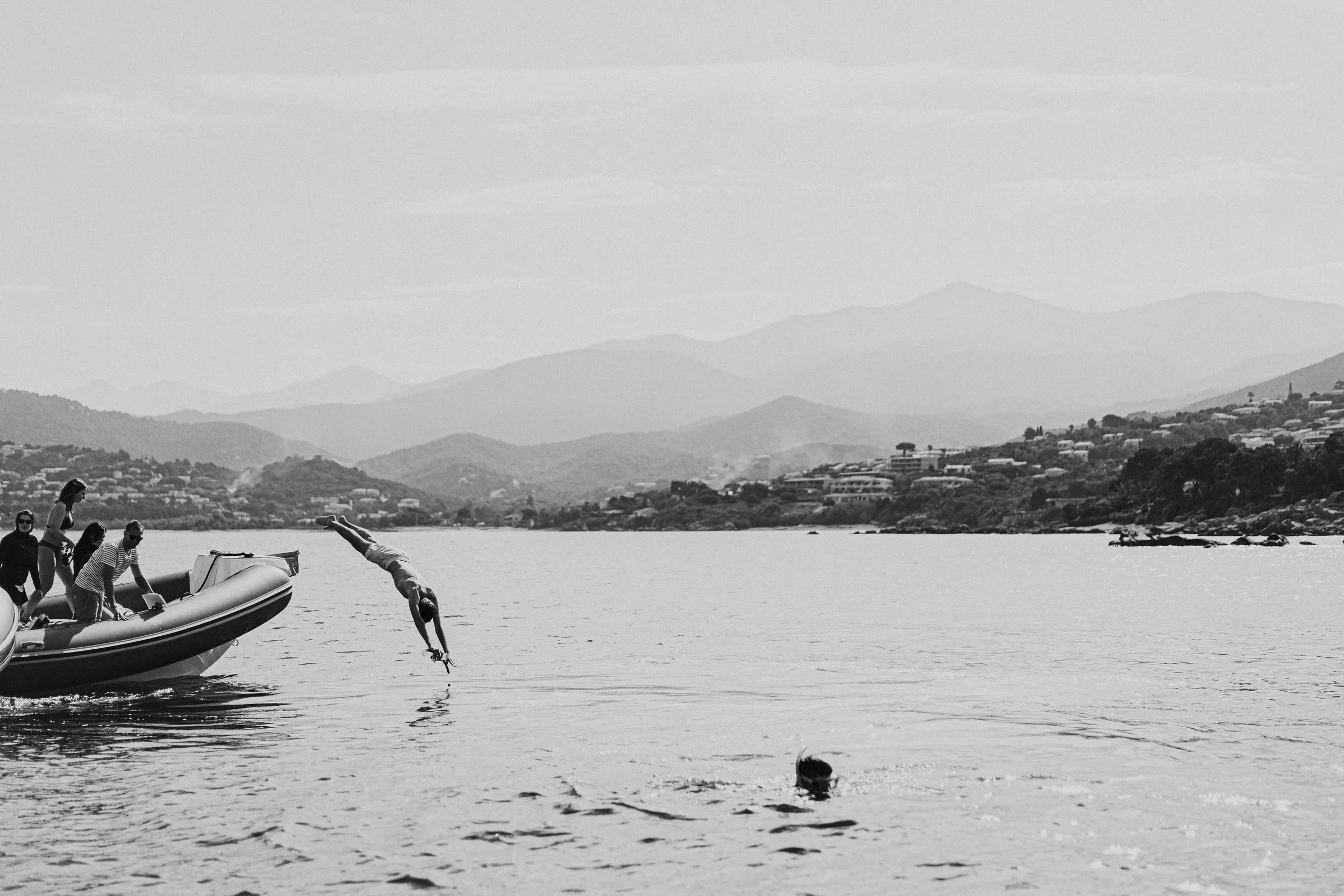 Groupe de personnes près d’un bateau à moteur sur un lac, avec montagnes en arrière-plan.