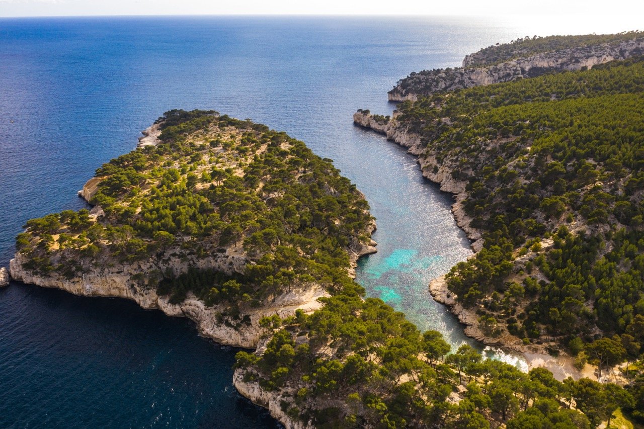 Vue aérienne des calanques de Marseille, avec falaises et eau turquoise.
