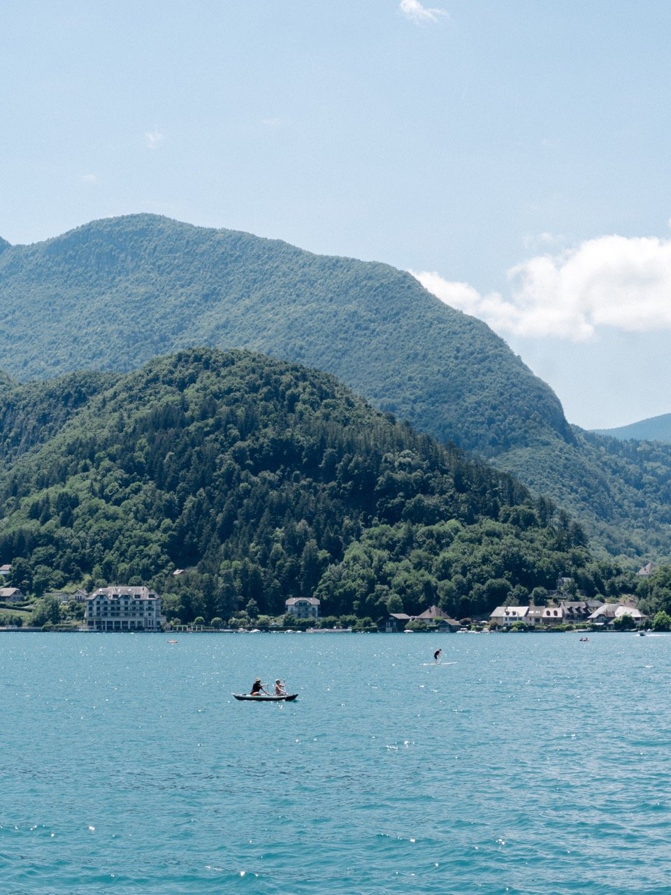 Paysage du lac d’Annecy avec des montagnes vertes en arrière-plan et un bateau dans l’eau