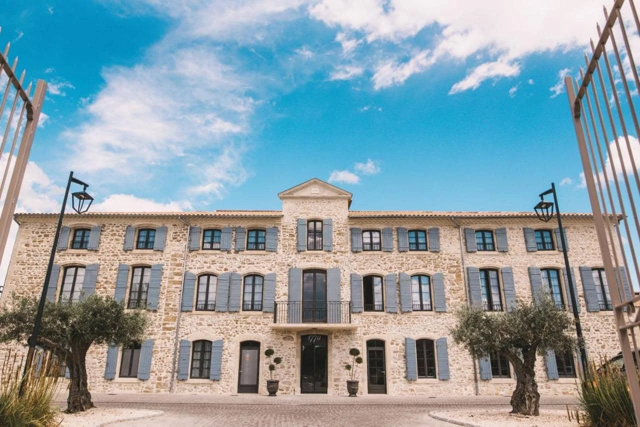 Façade en pierre de l'Hôtel 1770 à Avignon, une bâtisse provençale élégante avec des volets bleus, idéale pour un séminaire de charme.