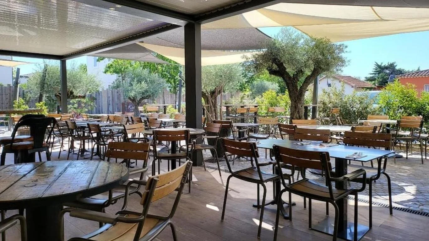 Terrasse extérieure du restaurant de l'Hôtel 1770, aménagée sous des oliviers, un cadre parfait pour les repas de groupe en Provence.