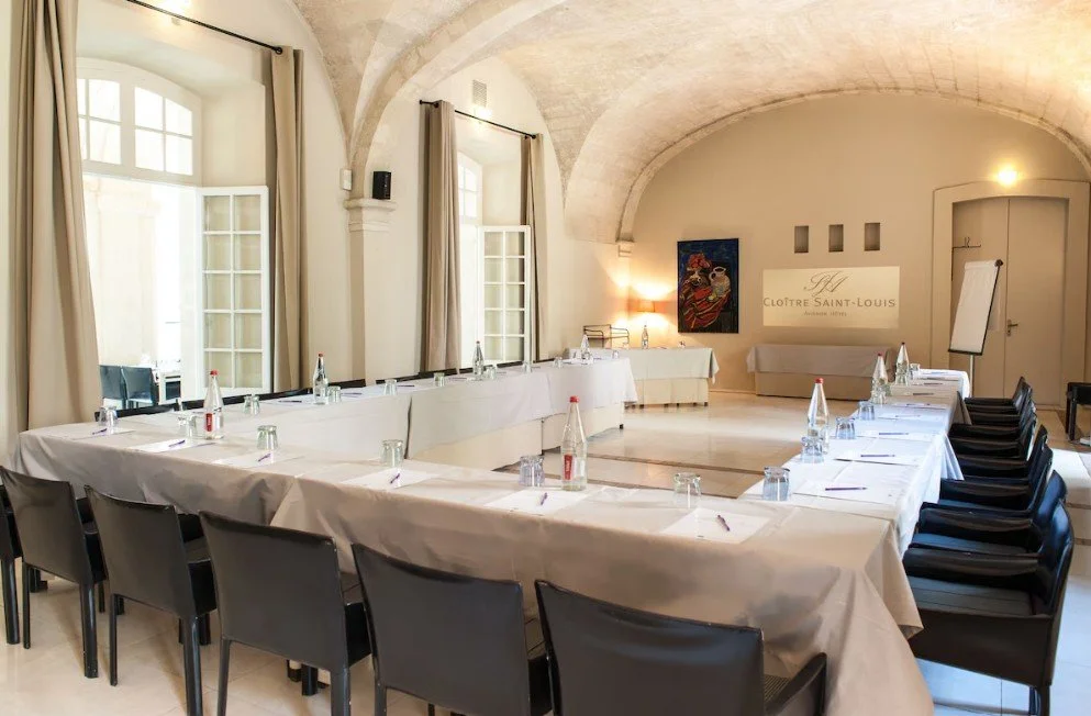 Grande salle de réunion de l'Hôtel Le Cloître Saint-Louis aménagée en U, parfaite pour les séminaires d'entreprise et les conventions.