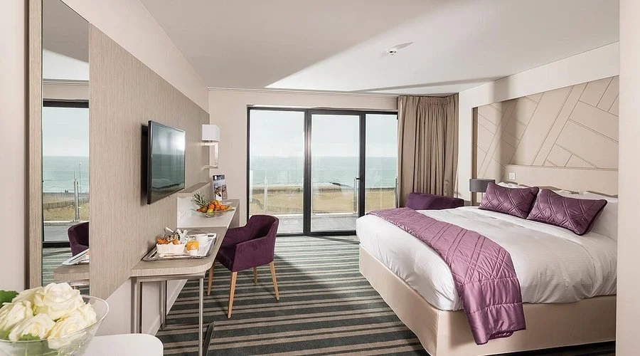 Chambre d’hôtel au design moderne à l’Hôtel des Bains Thalazur. L’espace dispose d’un lit king-size et d’un balcon avec vue directe sur la mer.